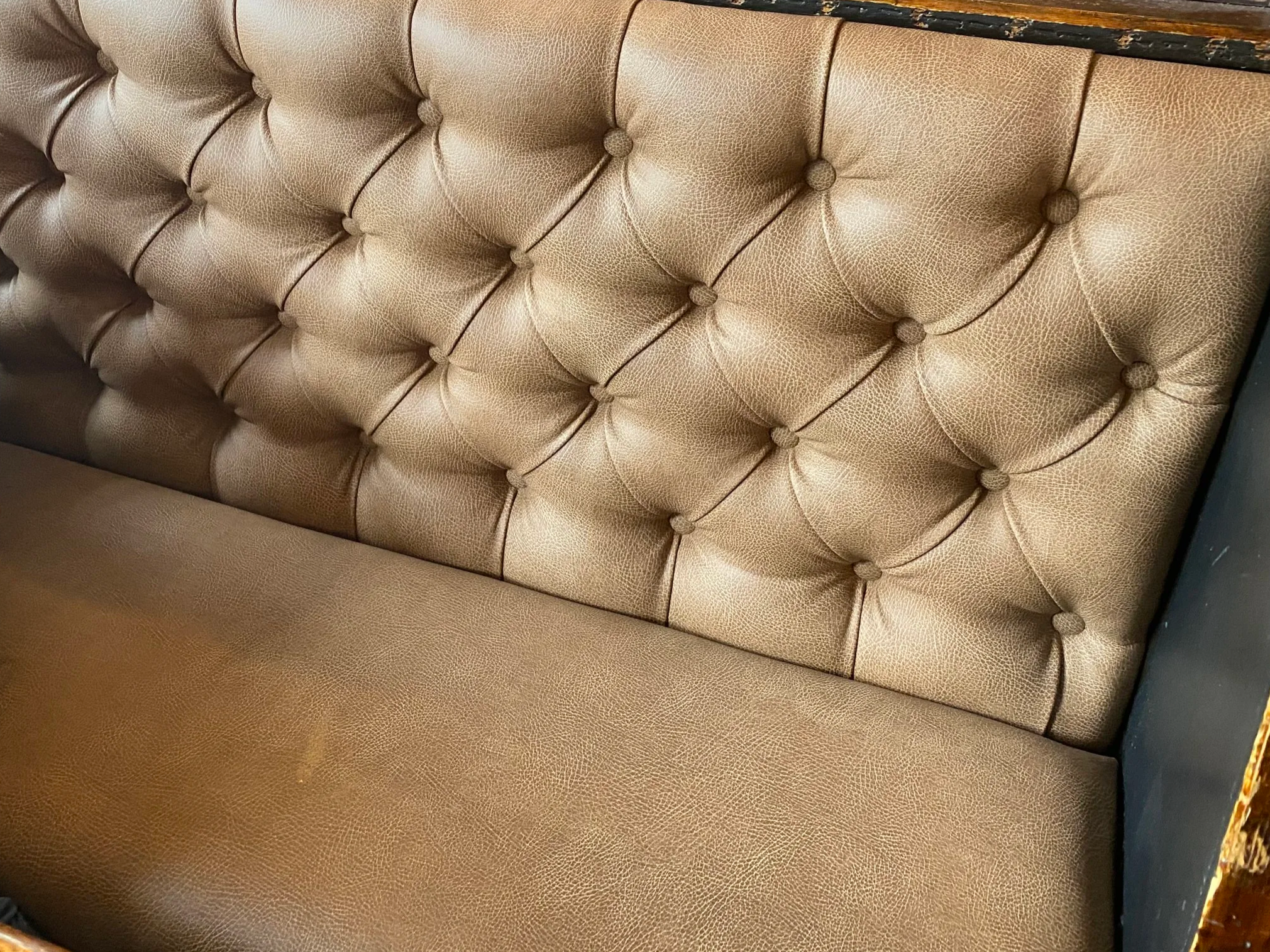 Close-up of a brown, buttoned, faux leather couch with a textured surface