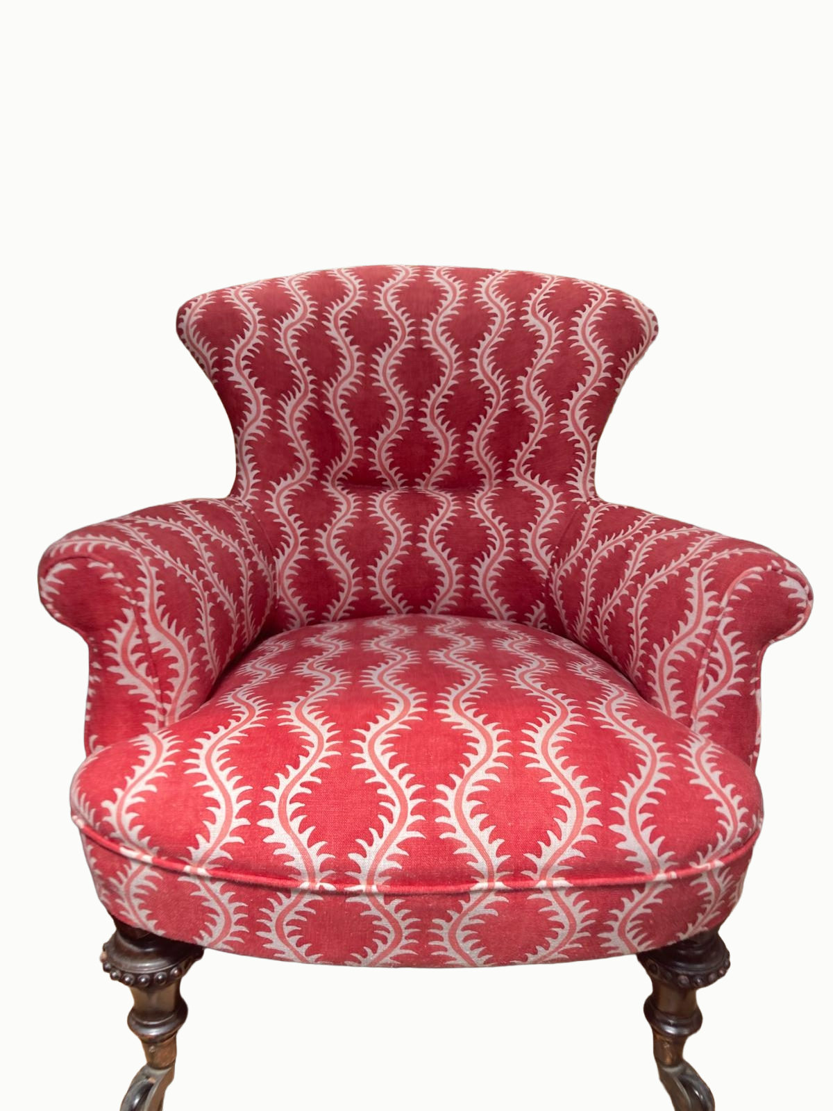 A red upholstered armchair with a white geometric pattern, carved wooden legs, and a high backrest.