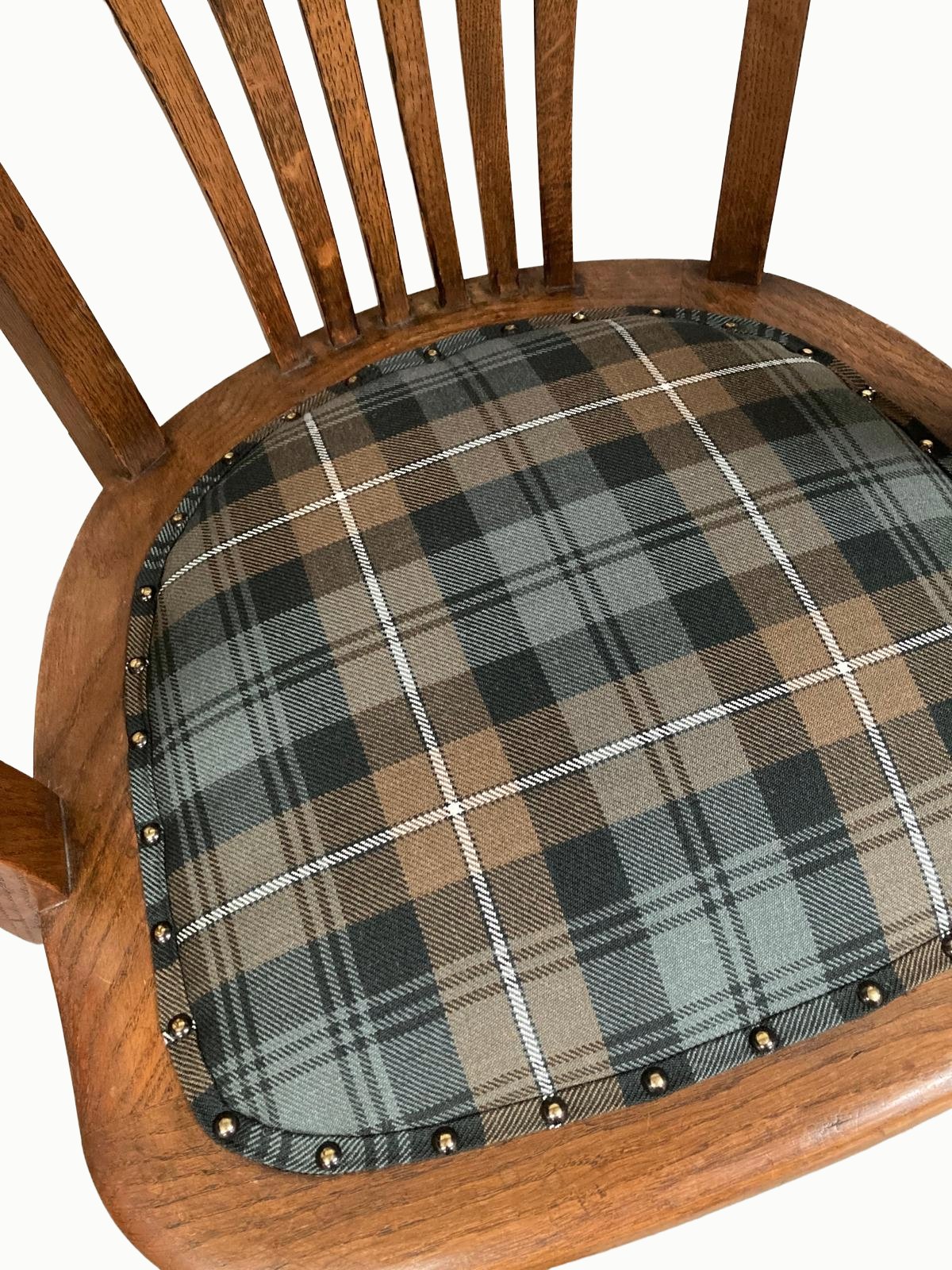 Close-up of a wooden chair with a plaid fabric cushioned seat featuring a pattern in shades of brown, black, and gray, decorated with small metallic nailhead trim along the edge.