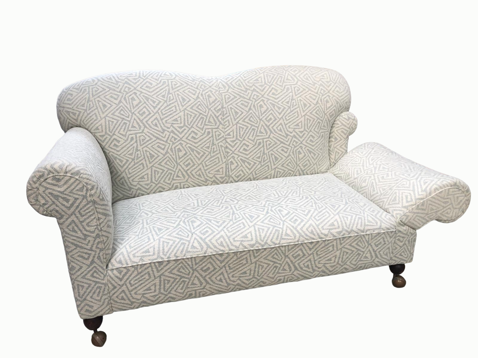 A vintage armchair with curved rolled arms, patterned fabric, and dark wooden castered legs.
