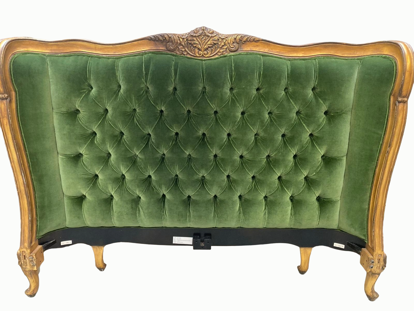 An antique green velvet upholstered head board with a carved wooden frame and cabriole legs.