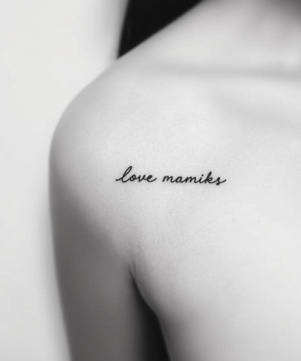 Close-up of a person's shoulder with a tattoo that reads 'love mamiks' in black cursive script.