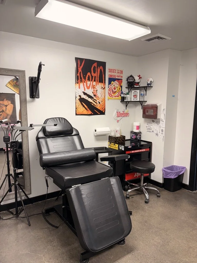 Tattoo chair in a tattoo parlor with shelves, posters, and equipment.