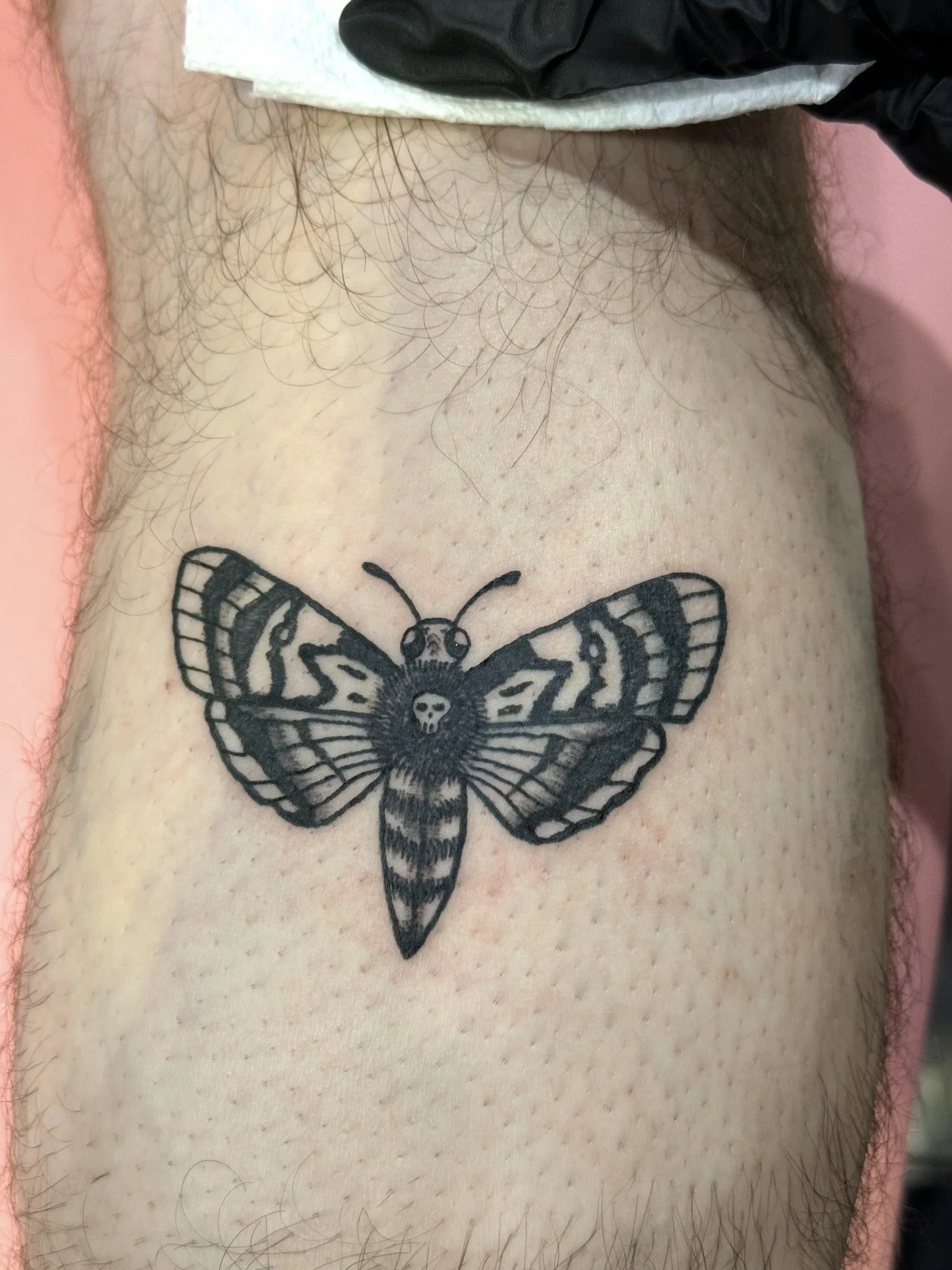 Black and white tattoo of a moth with detailed wings on a person's skin.