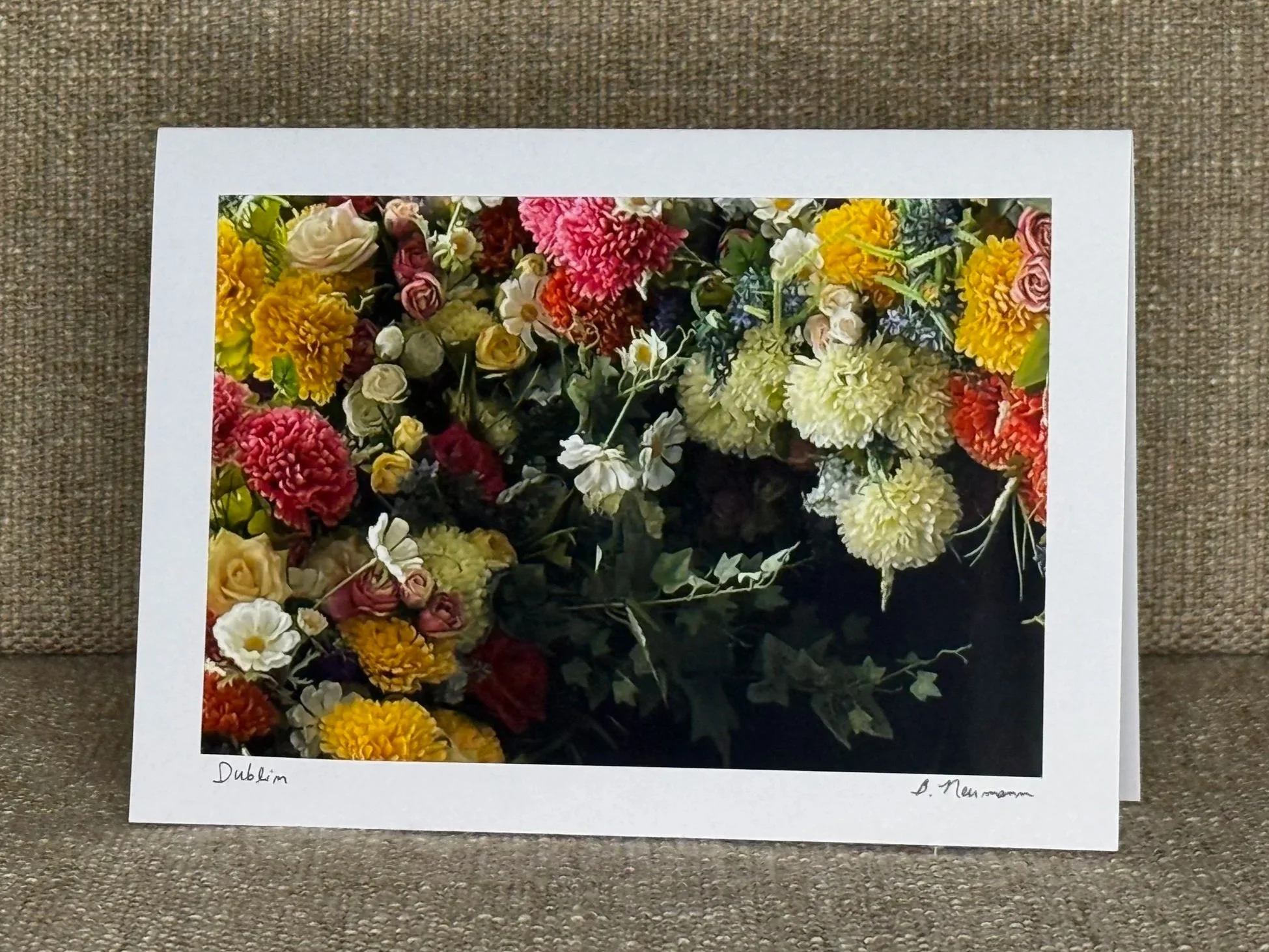 A framed print of a colorful flower arrangement resting on a brown textured surface.