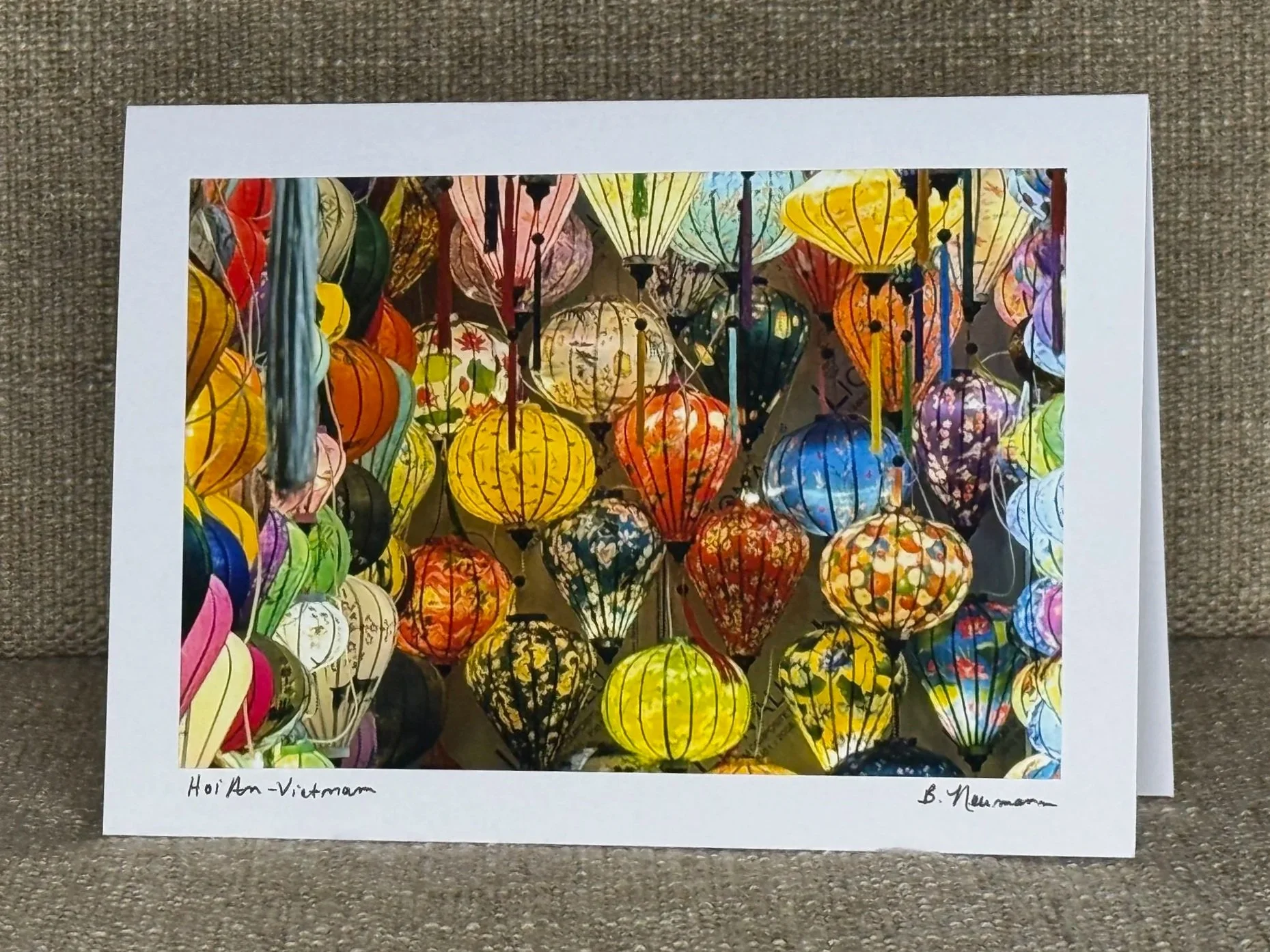 A colorful collection of hanging lanterns in various shapes, sizes, and patterns, illuminated and displayed together.