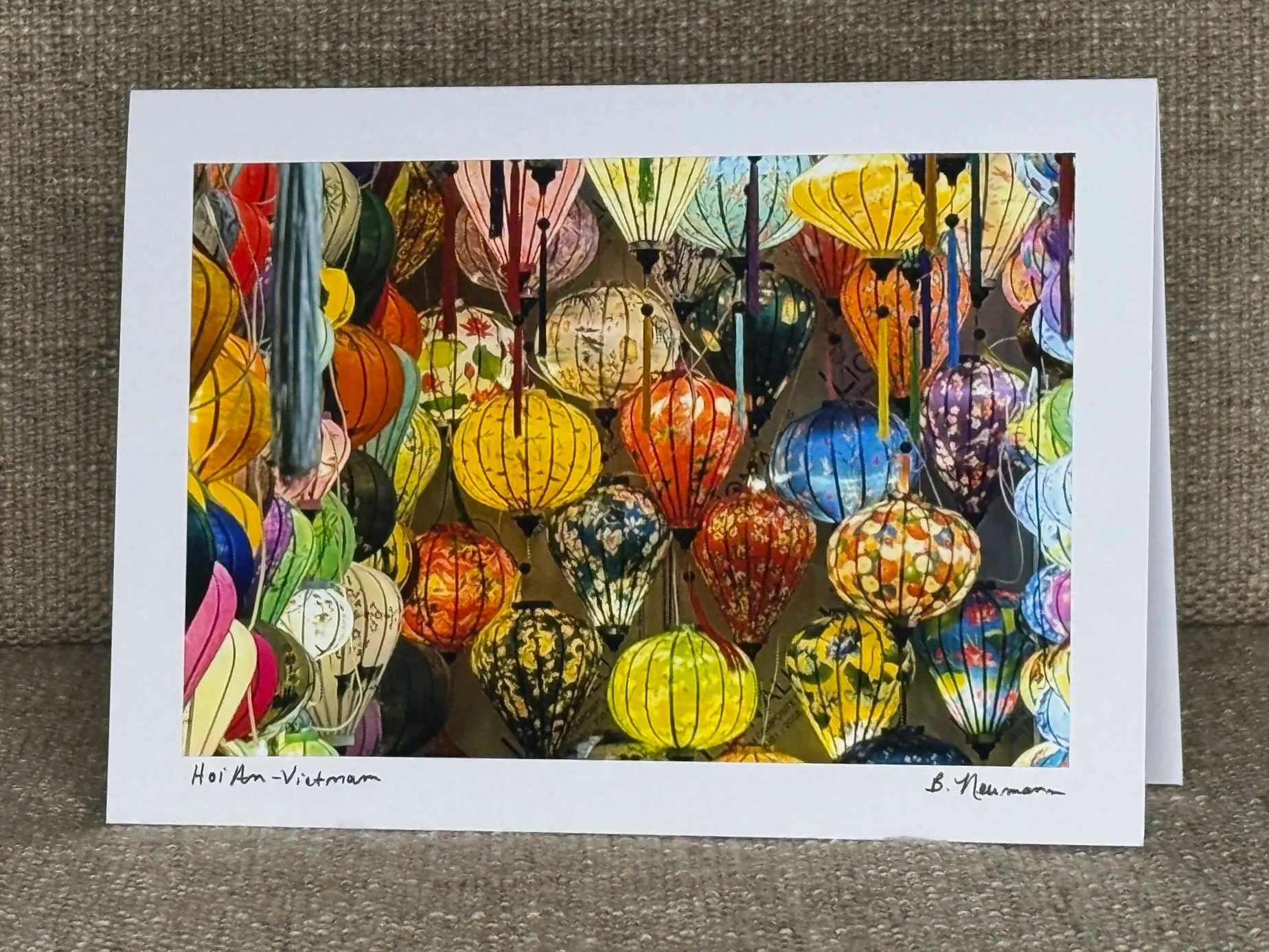Photograph of colorful paper lanterns hanging in the air, illuminated against a dark background.