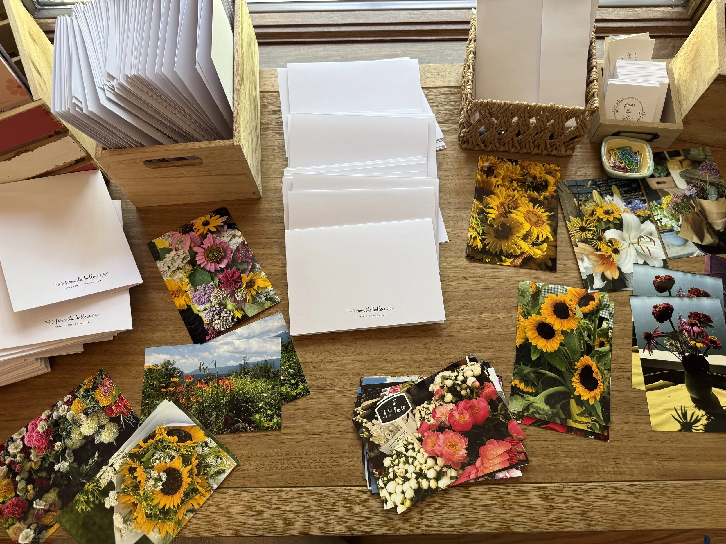 Display of flower postcards and greeting cards arranged on a wooden table.