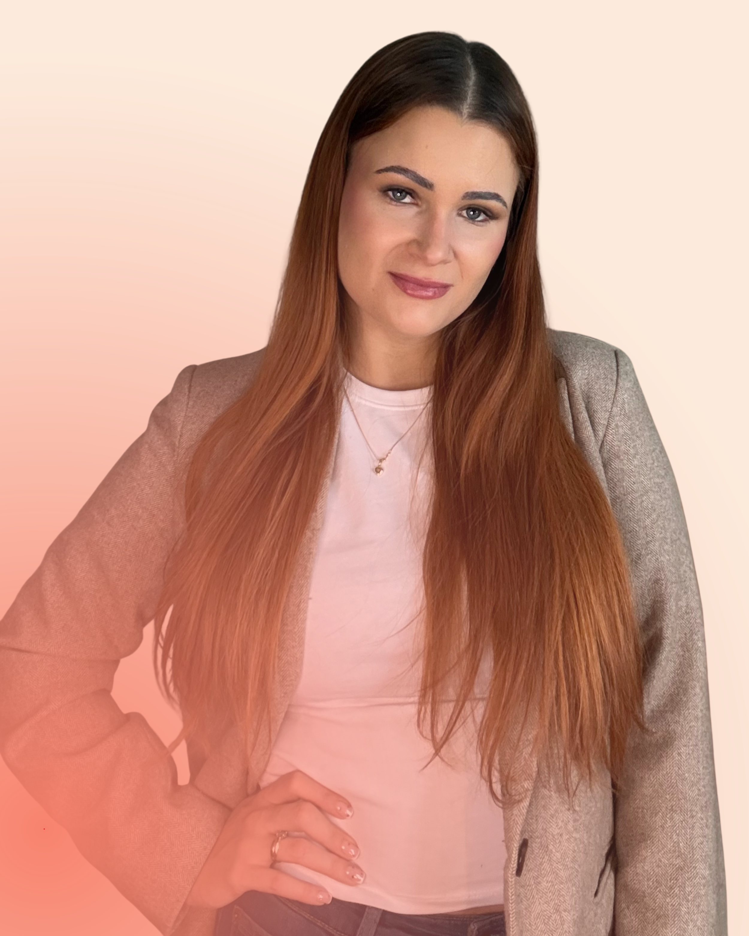 A woman with long reddish-brown hair, wearing a light pink shirt and a beige blazer, poses with one hand on her hip against a gradient background transitioning from cream to soft pink.