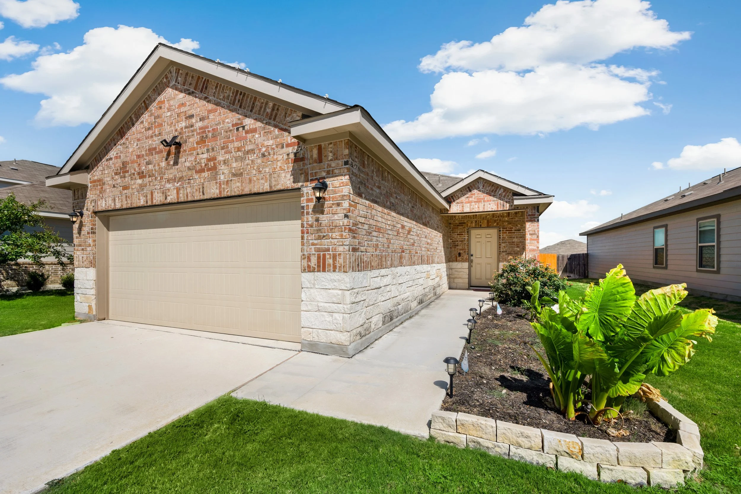 Brick and stone single-family home for sale in Bloomington, Indiana with two-car garage, covered entry, and landscaped front yard