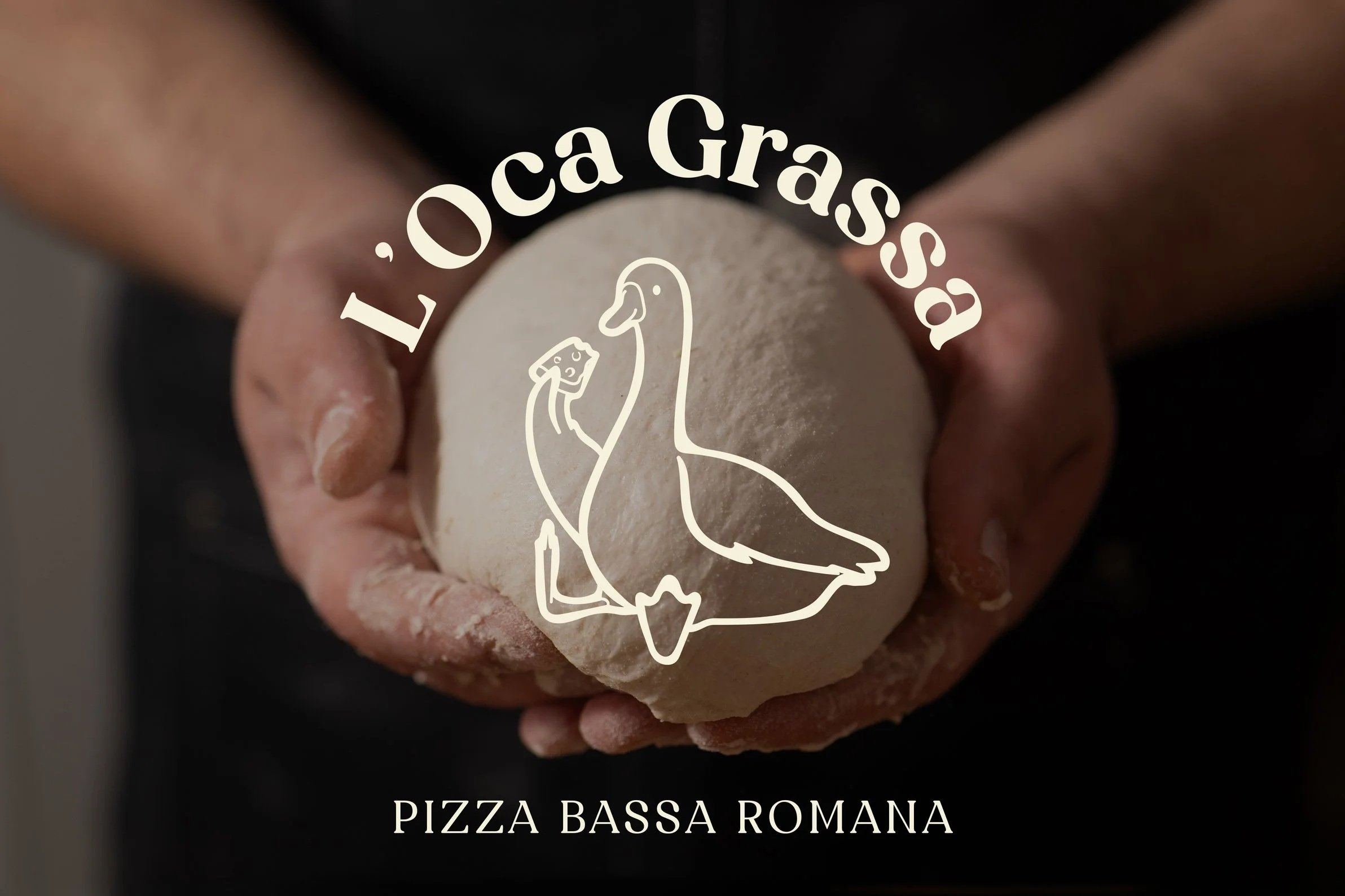 Un pane in mano con un logo di una papera e la scritta 'L'Oca Gassà'.