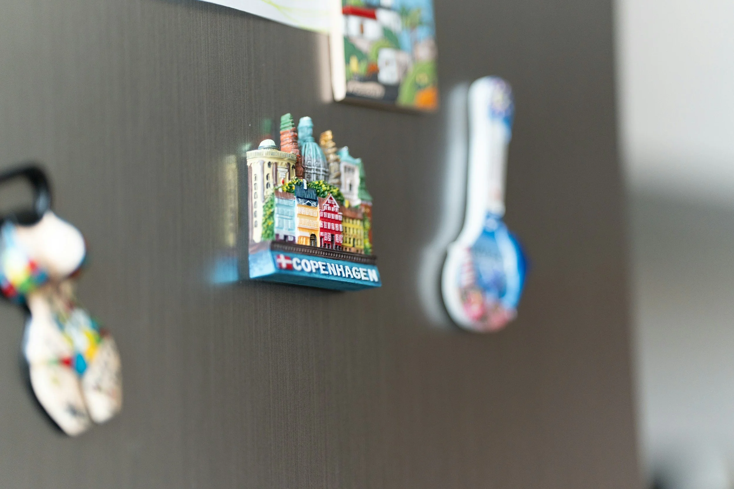 Colorful magnets on a refrigerator door, including a magnet with the word 'COPENHAGEN' and illustrations of city buildings.