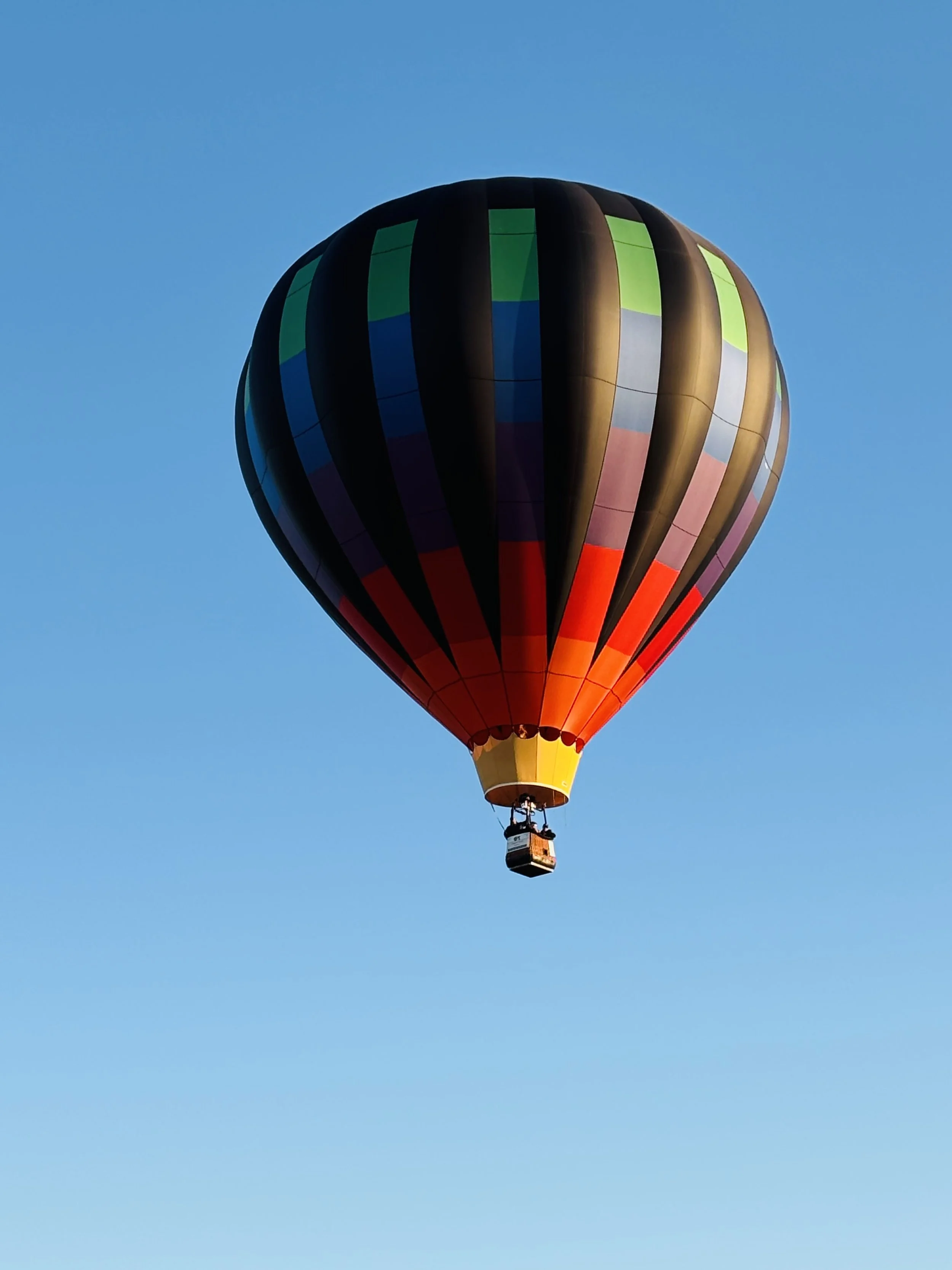 Colorful hot air balloon floating in a clear blue sky.