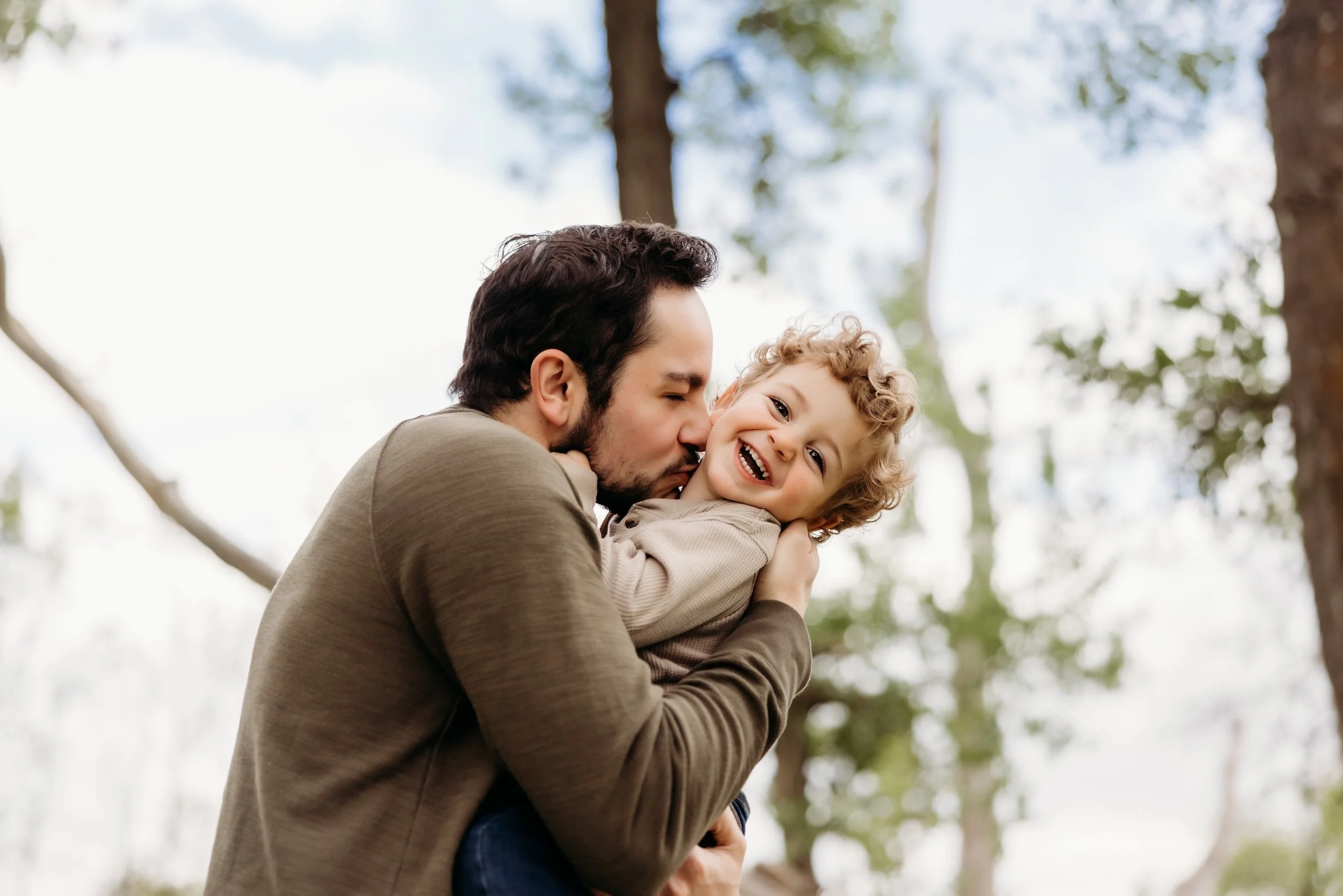 Dad kissing a laughing toddler.