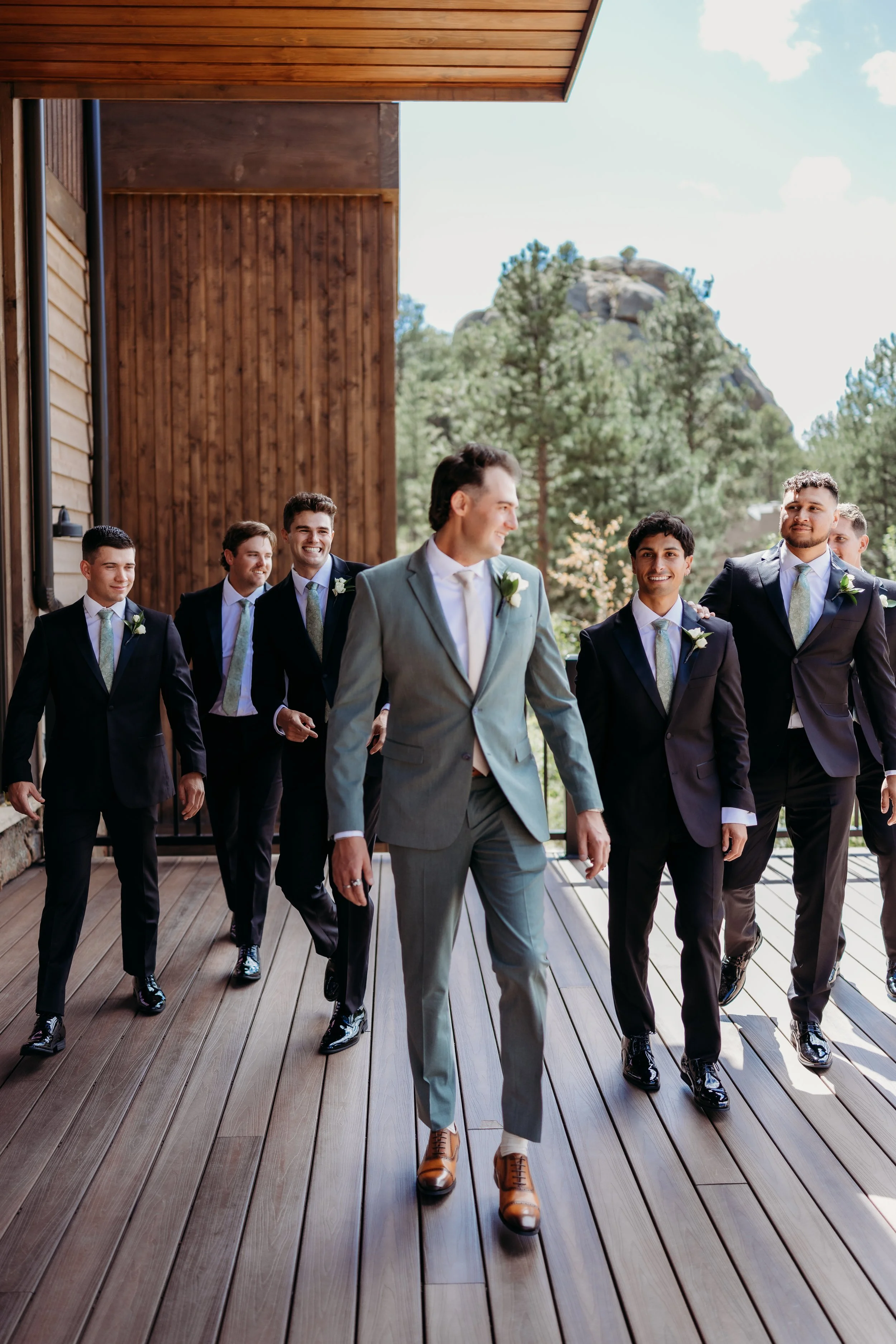 A groom and his groomsmen walking on a porch.