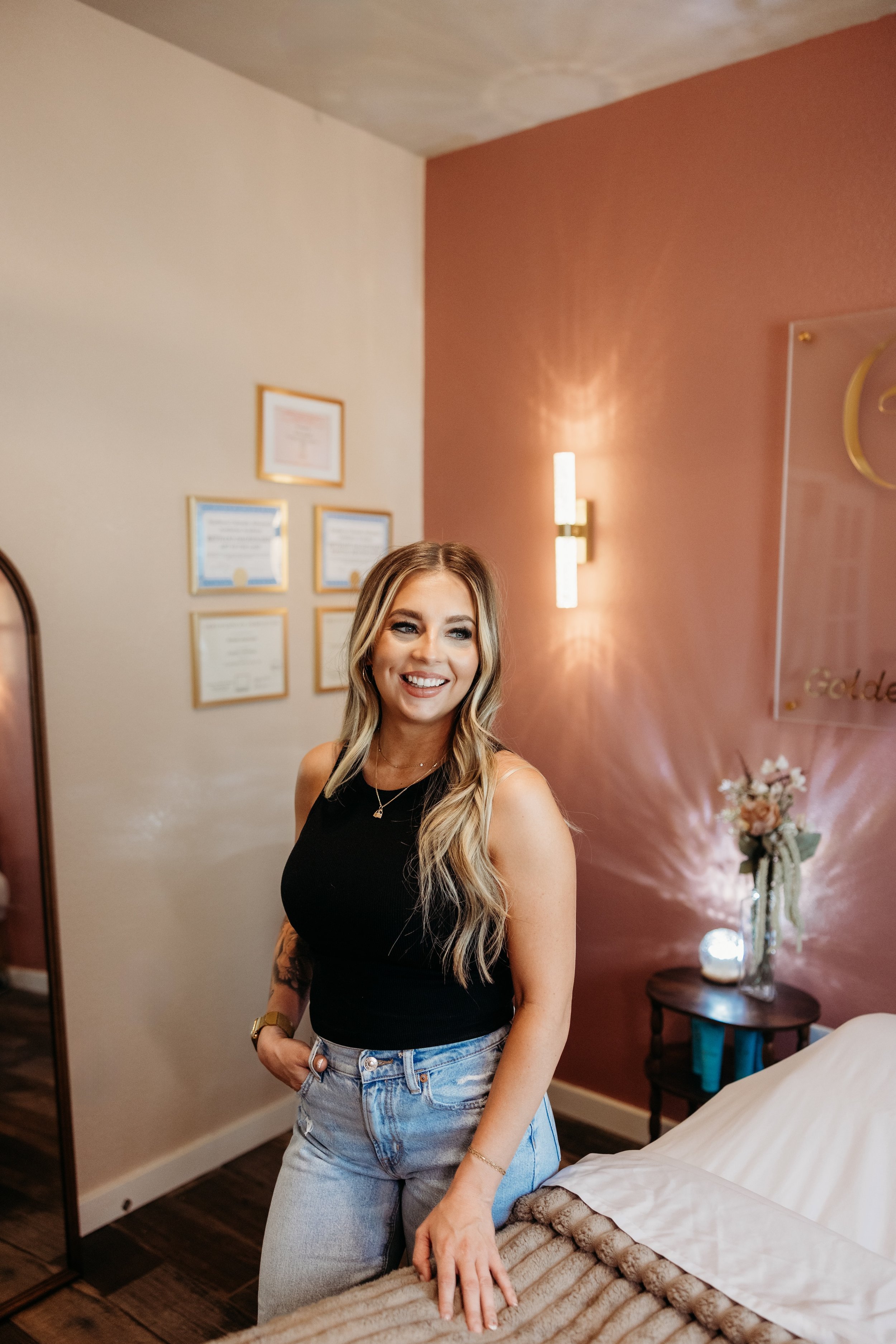 Woman smiling and posing next to a bed.