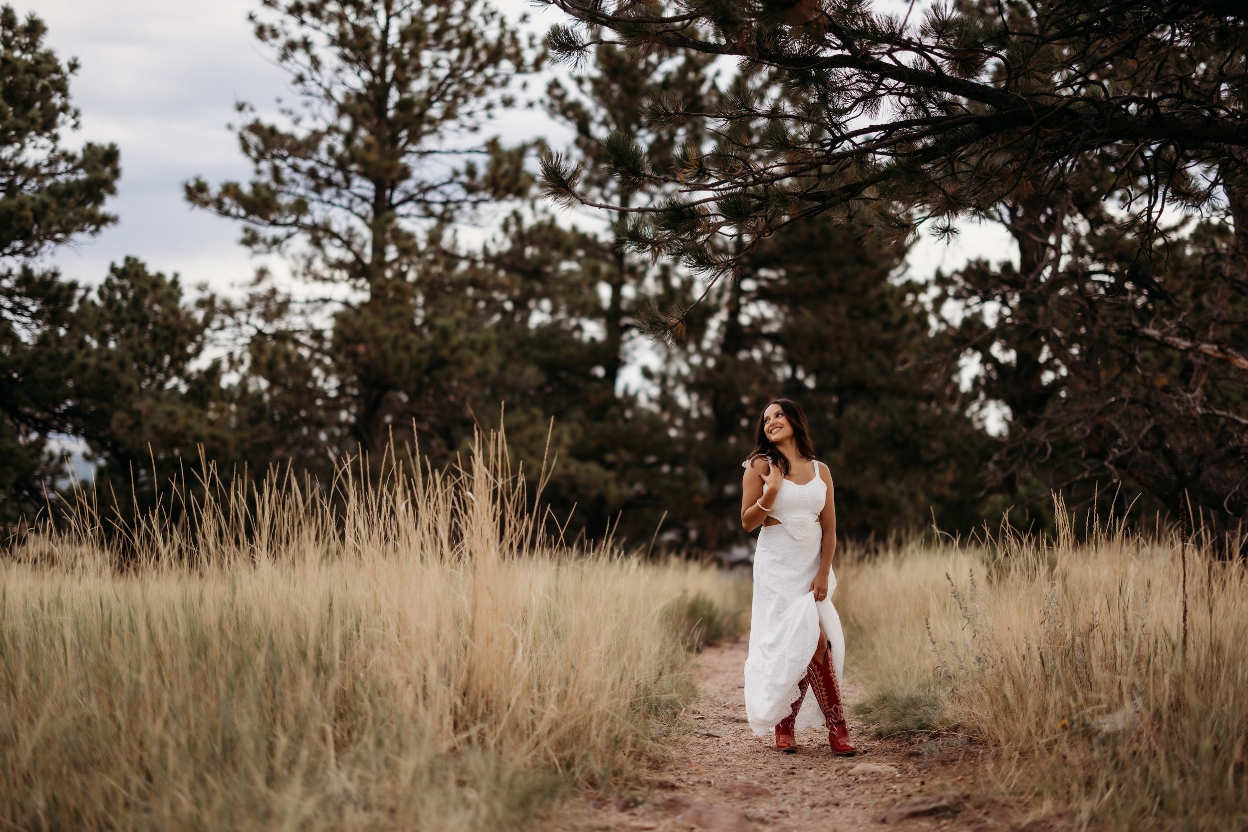 Girl in a white dress posing in a mountain field.