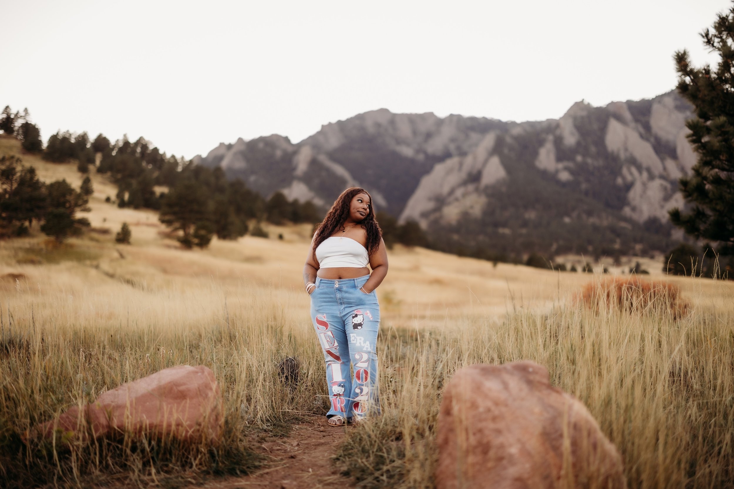 Teenage girl in ripped jeans posing in front of the mountains in Boulder, Colorado.
