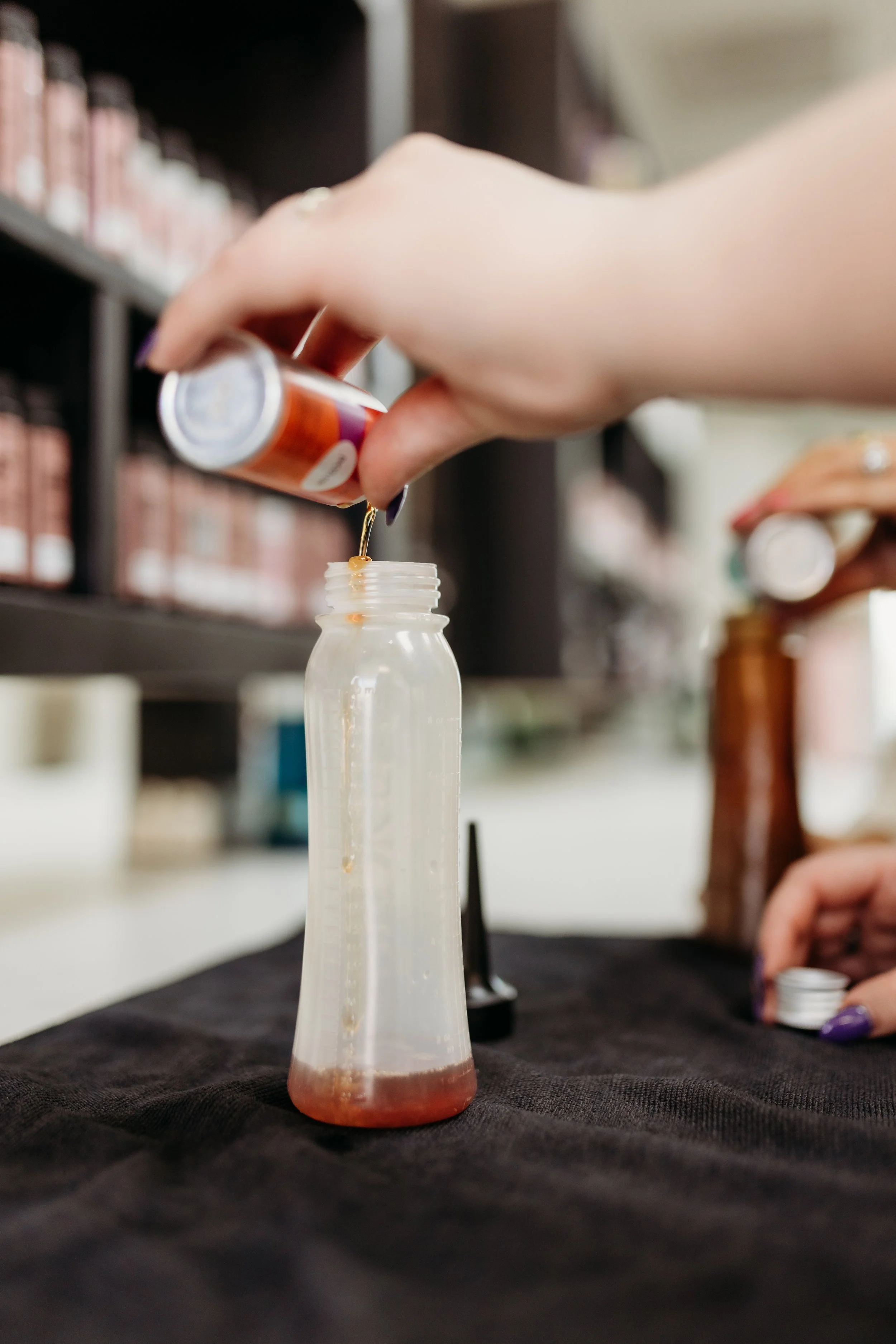 Person pouring hair dye into a bottle.