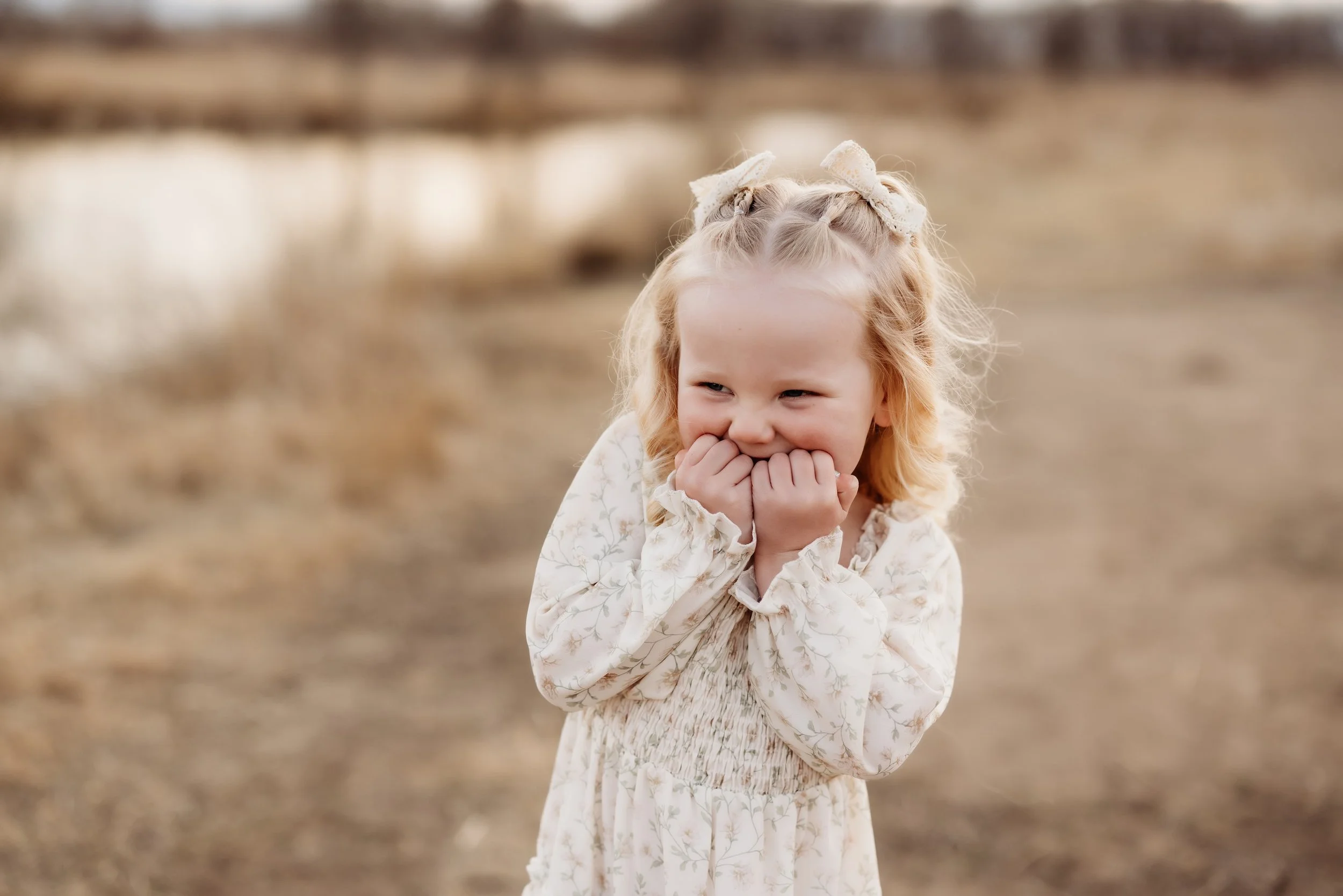 Young girl laughing with her hands on her face.