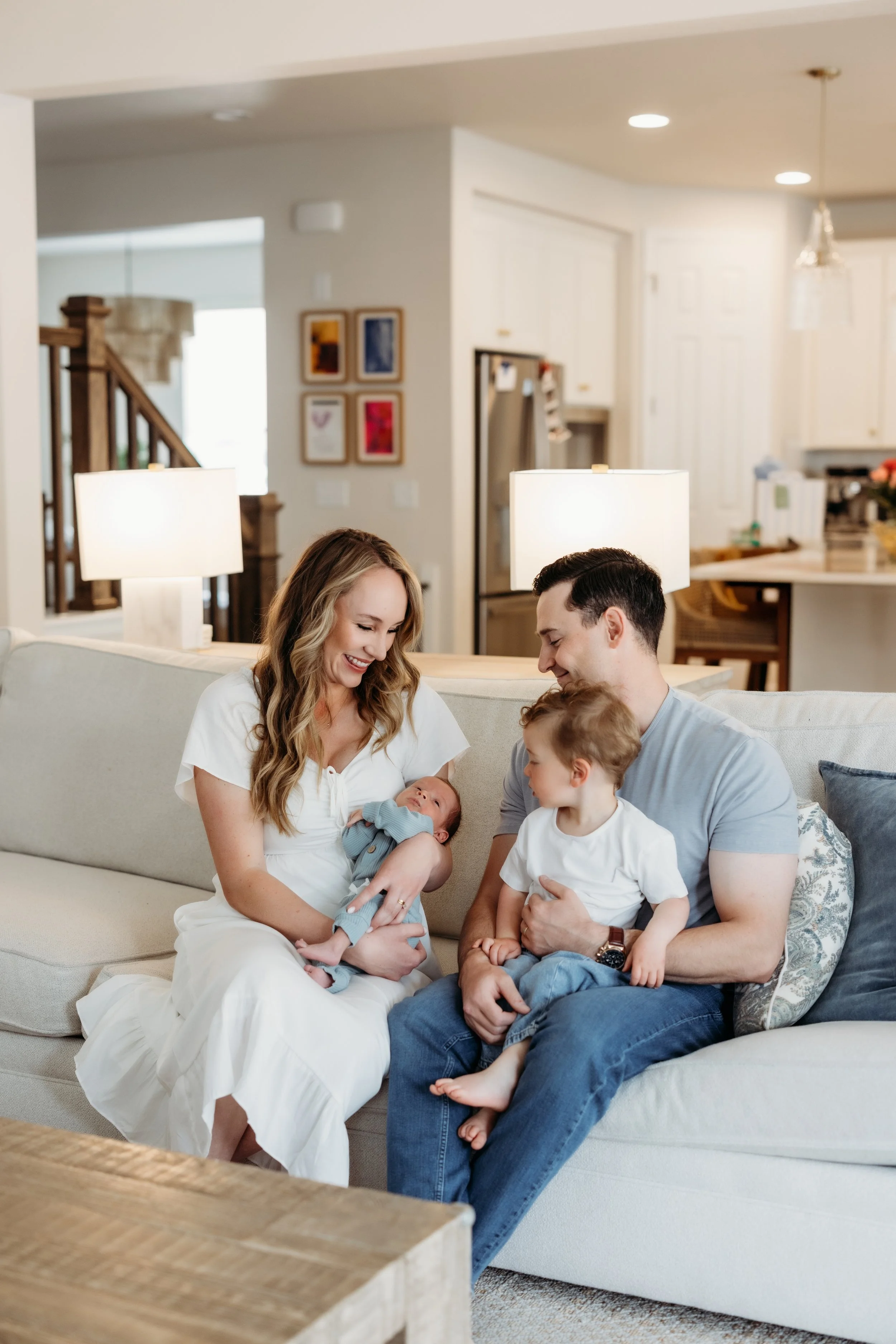 Two parents and a toddler smiling a a newborn baby.
