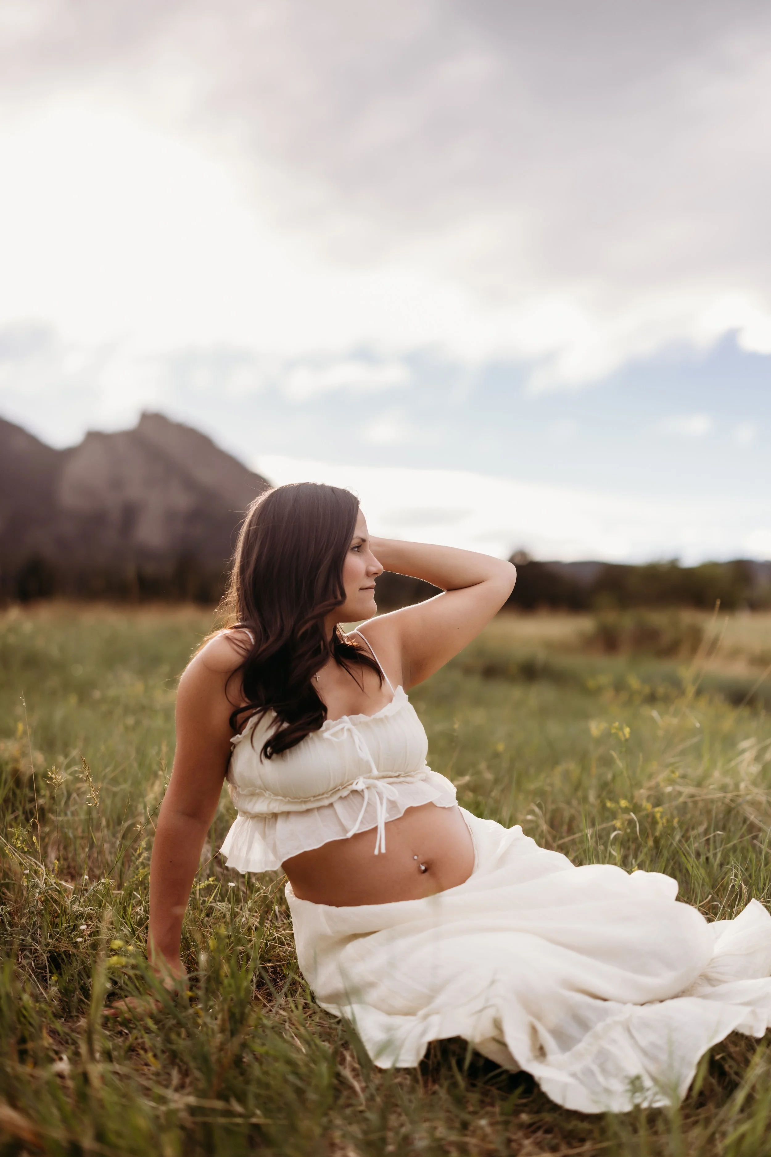 Pregnant woman sitting in the grass at Chautauqua Park in Boulder, Colorado.