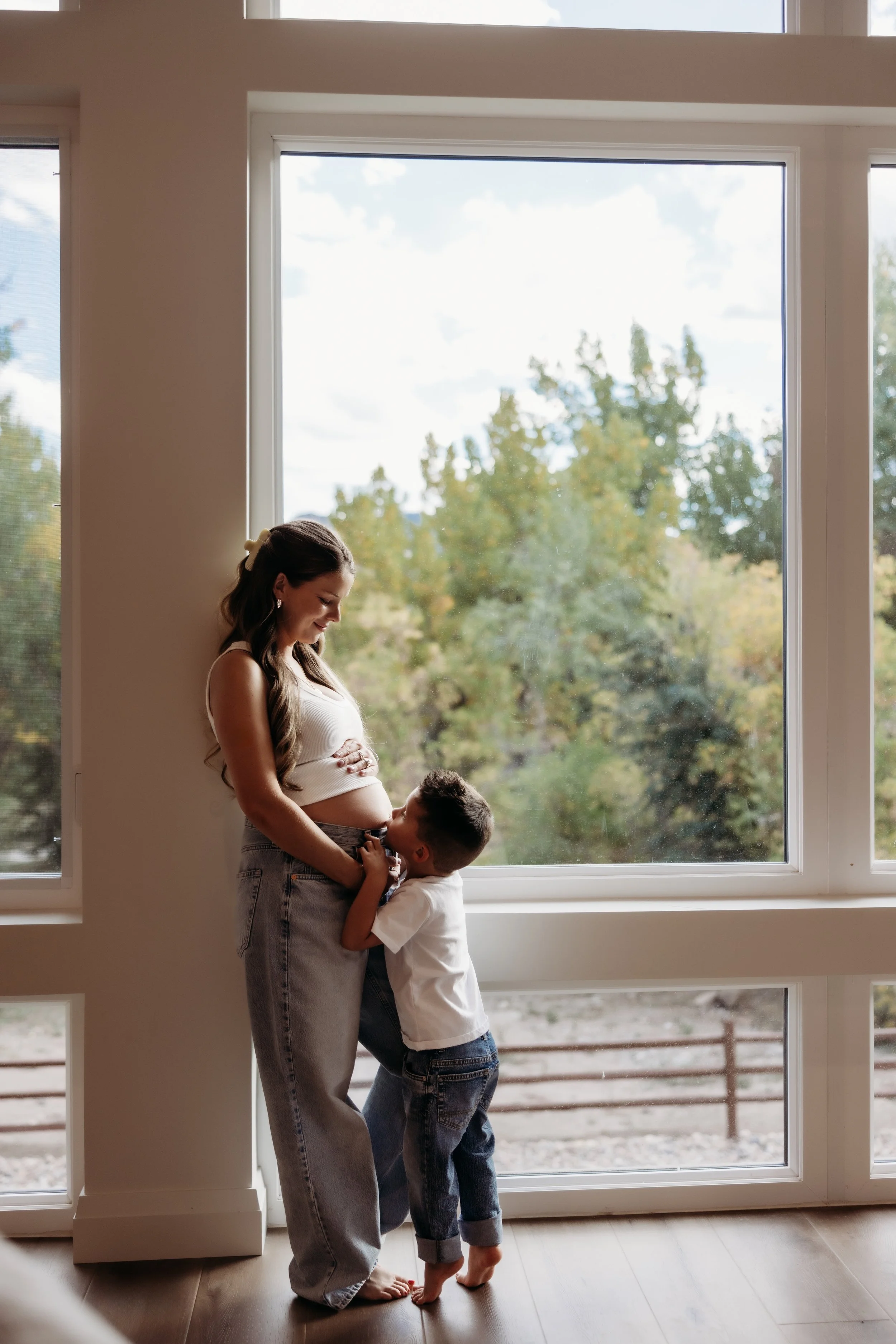 Boy kissing his mother's pregnant belly.