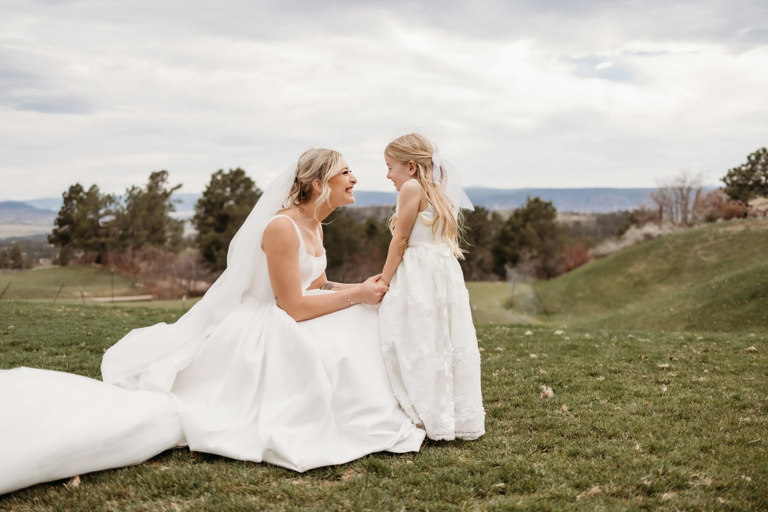 Bride smiling at a flower girl at Sanctuary Golf Course.