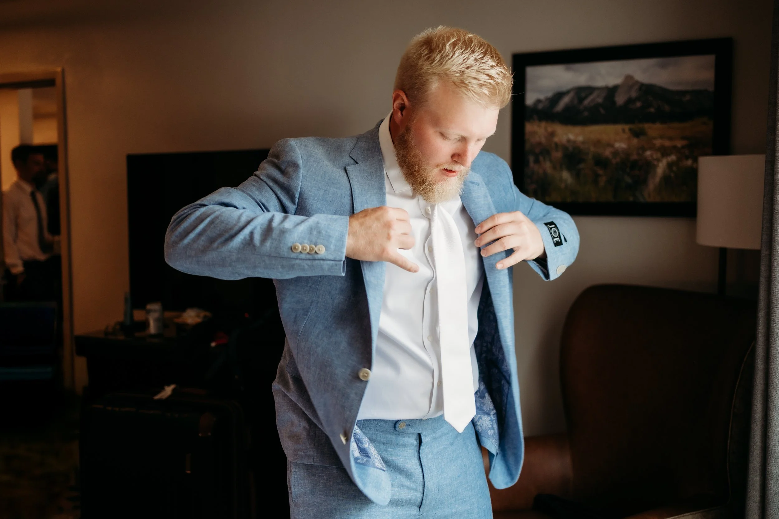Groom adjusting his blue suit.