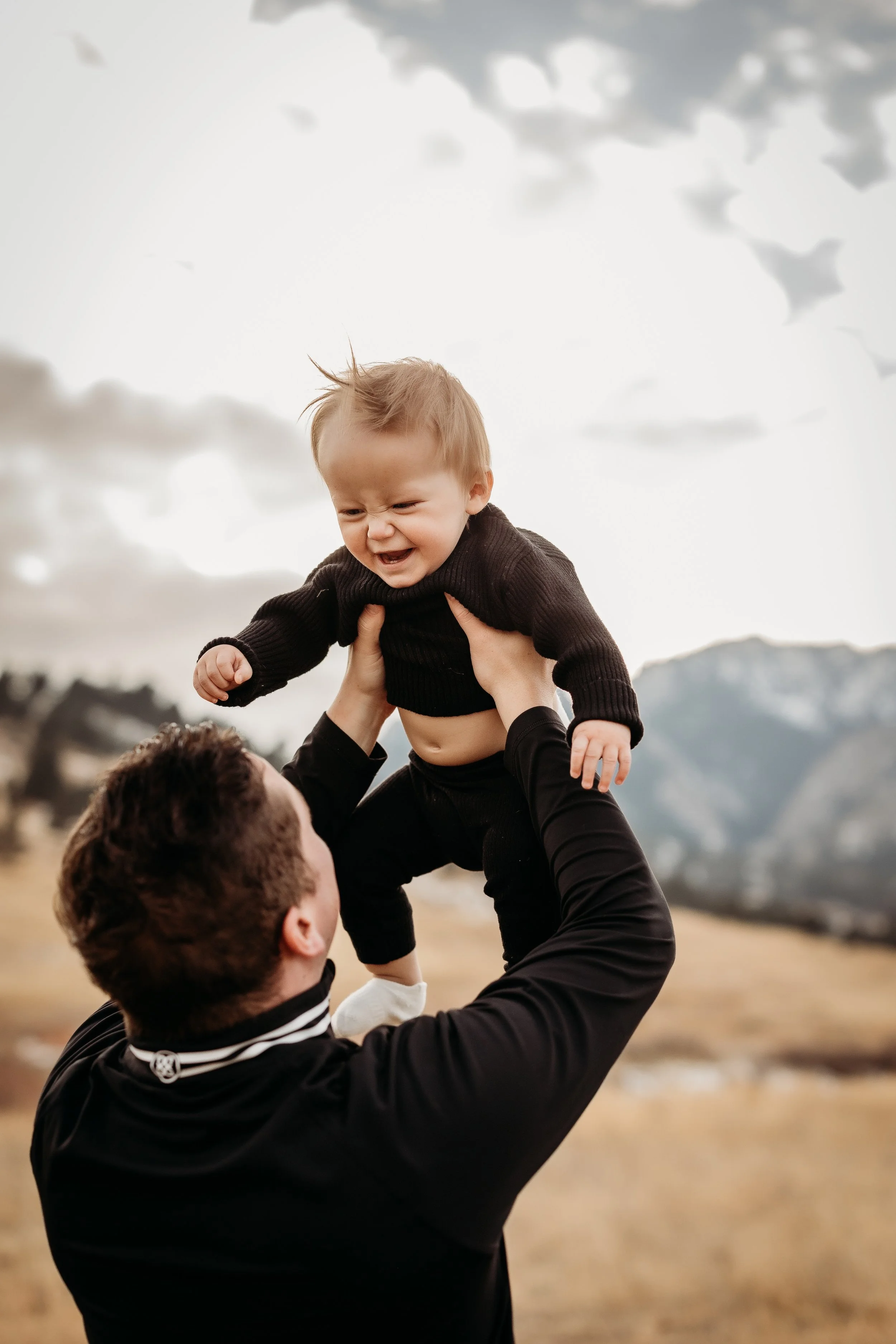 Dad lifting a smiling baby at Chautauqua Park in Boulder, Colorado.