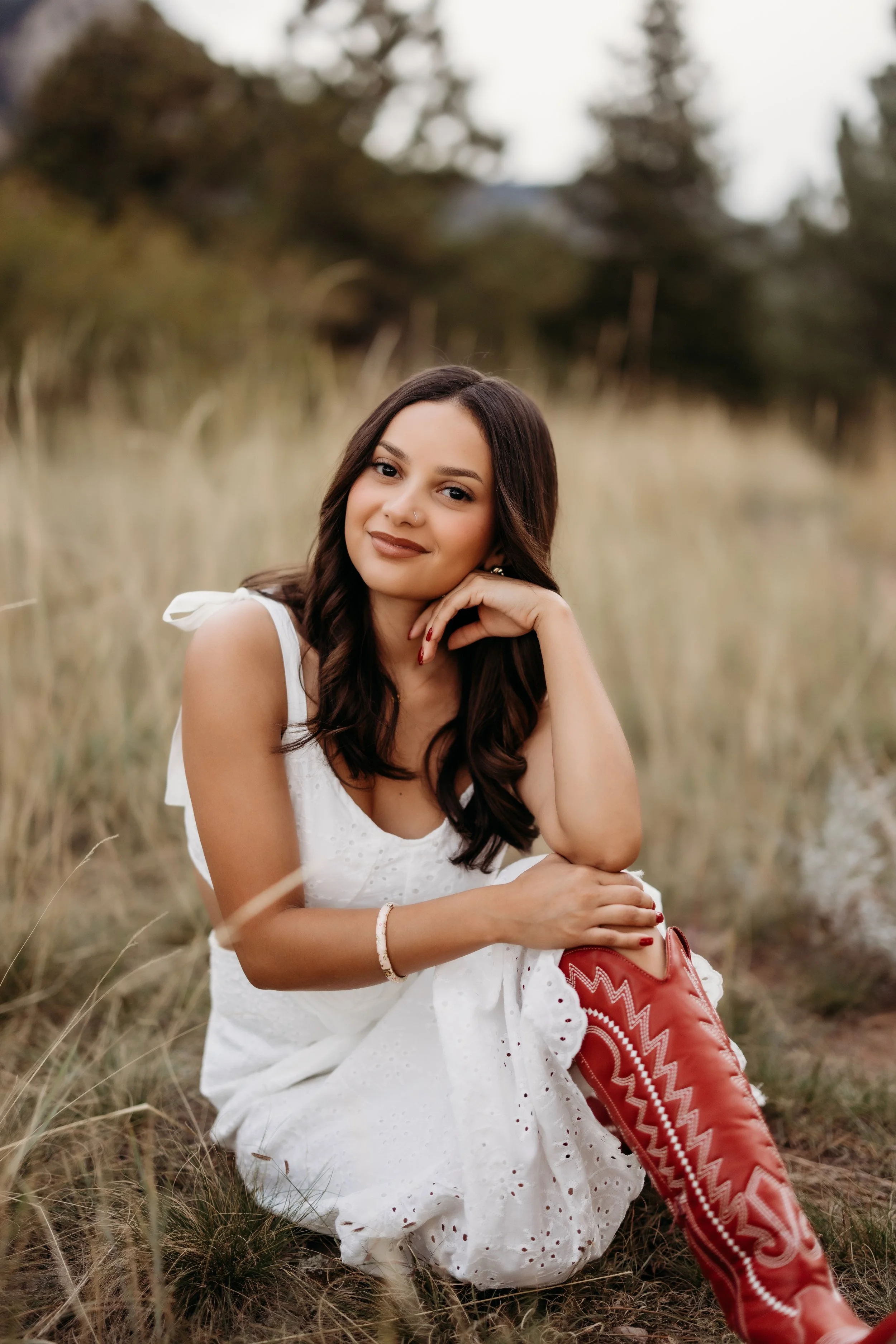 Teenage girl sitting on the ground posing in red cowboy boots.
