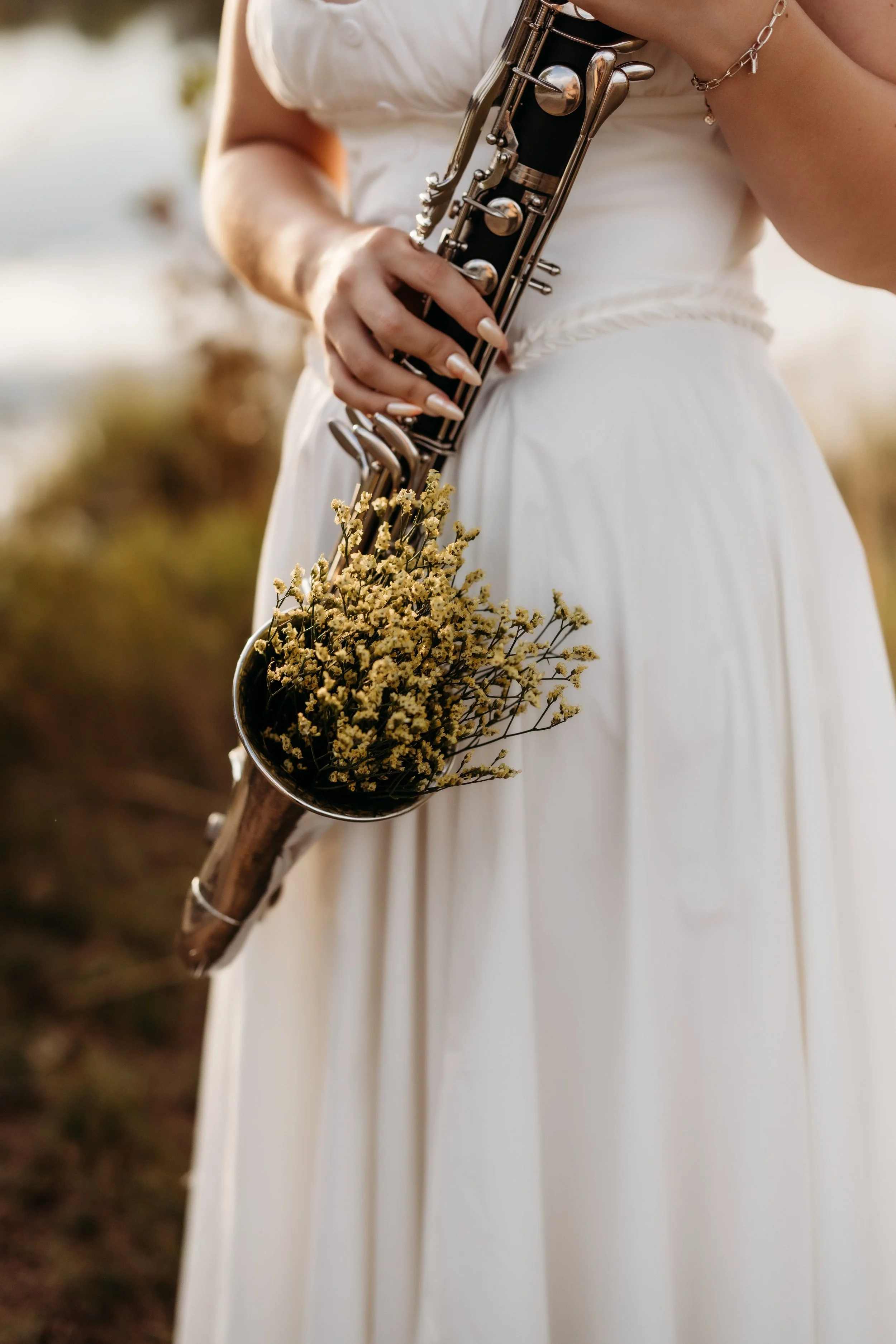 Girl holding a saxophone with yellow flowers inside.
