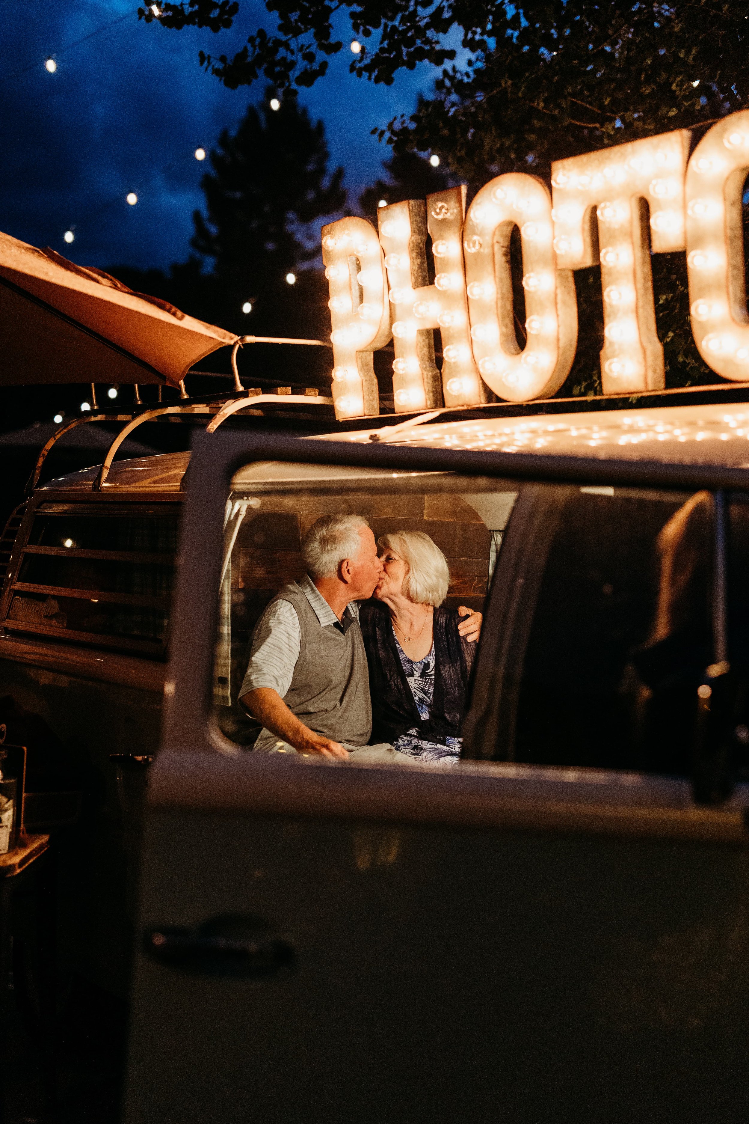 Senior bride and groom kissing in a photo booth. 