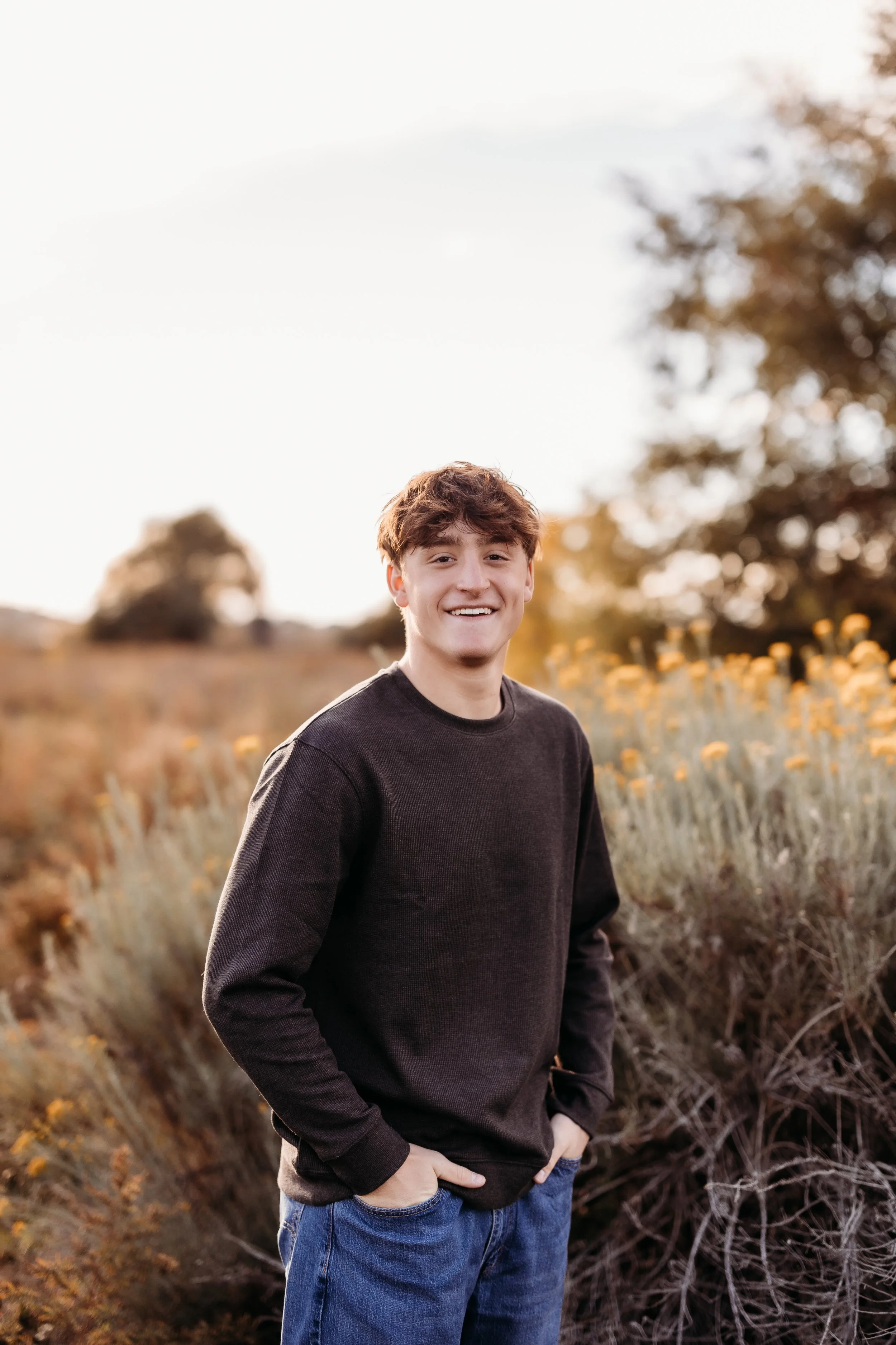 Senior boy smiling with his hands in his pockets.