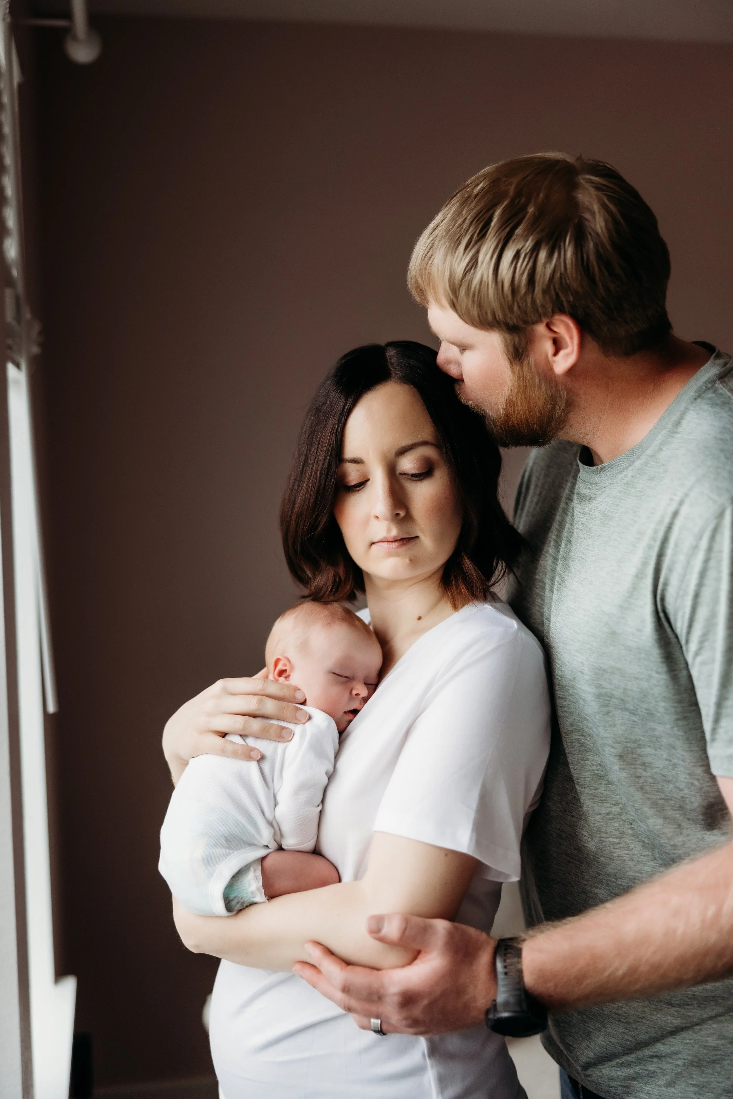 Parents embracing a sleeping newborn.