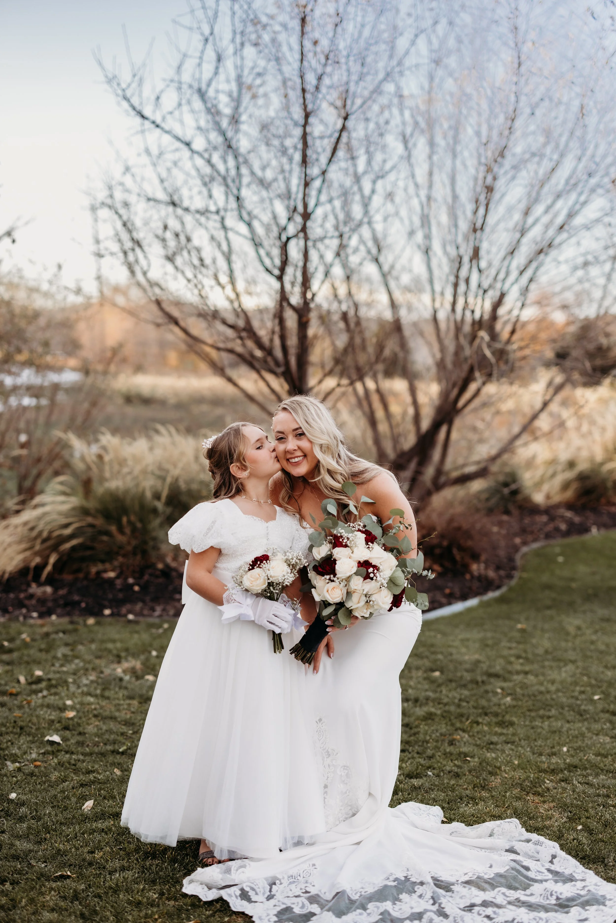 Flower girl kissing the bride on the cheek.