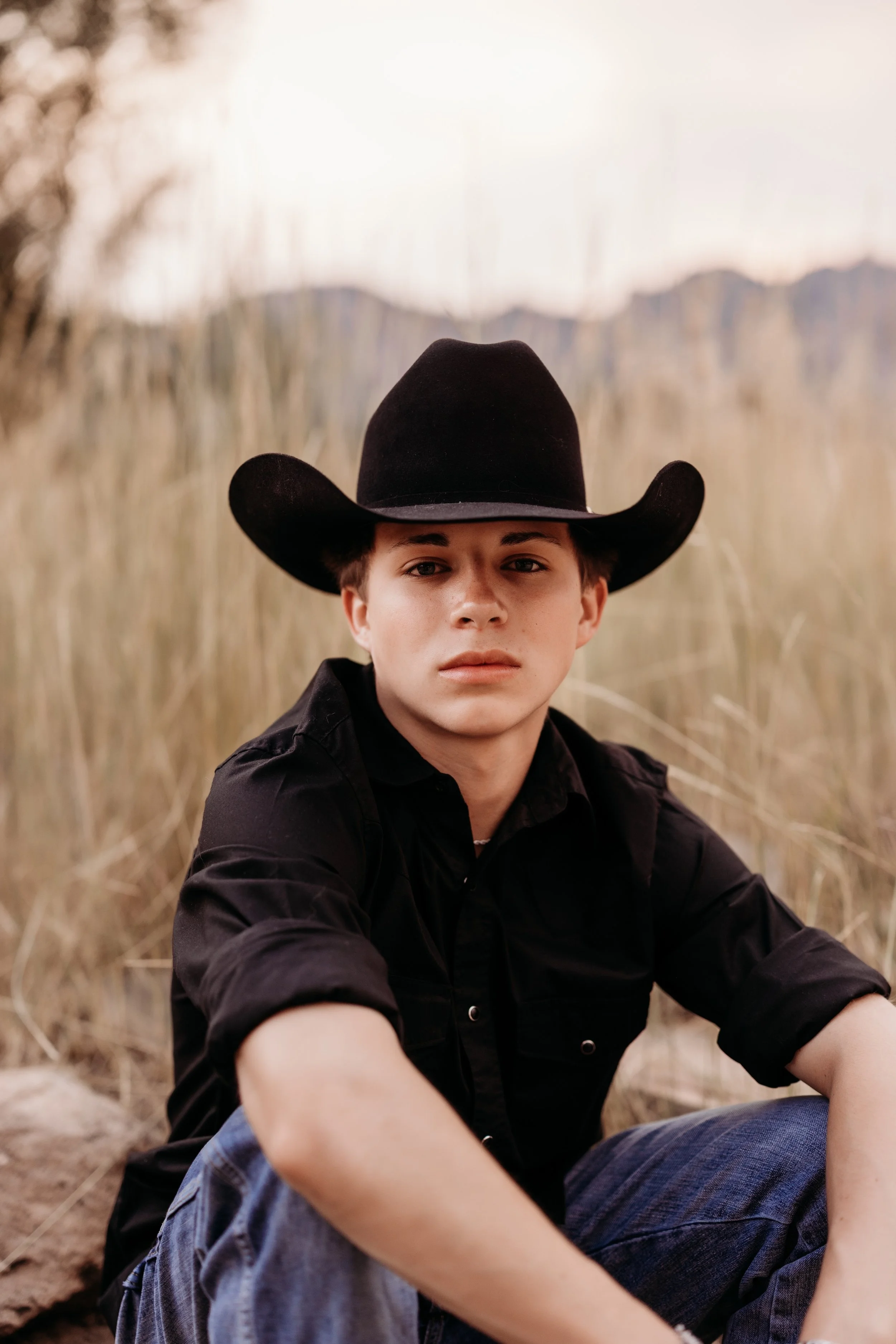 Boy wearing a black cowboy hat with a serious expression.
