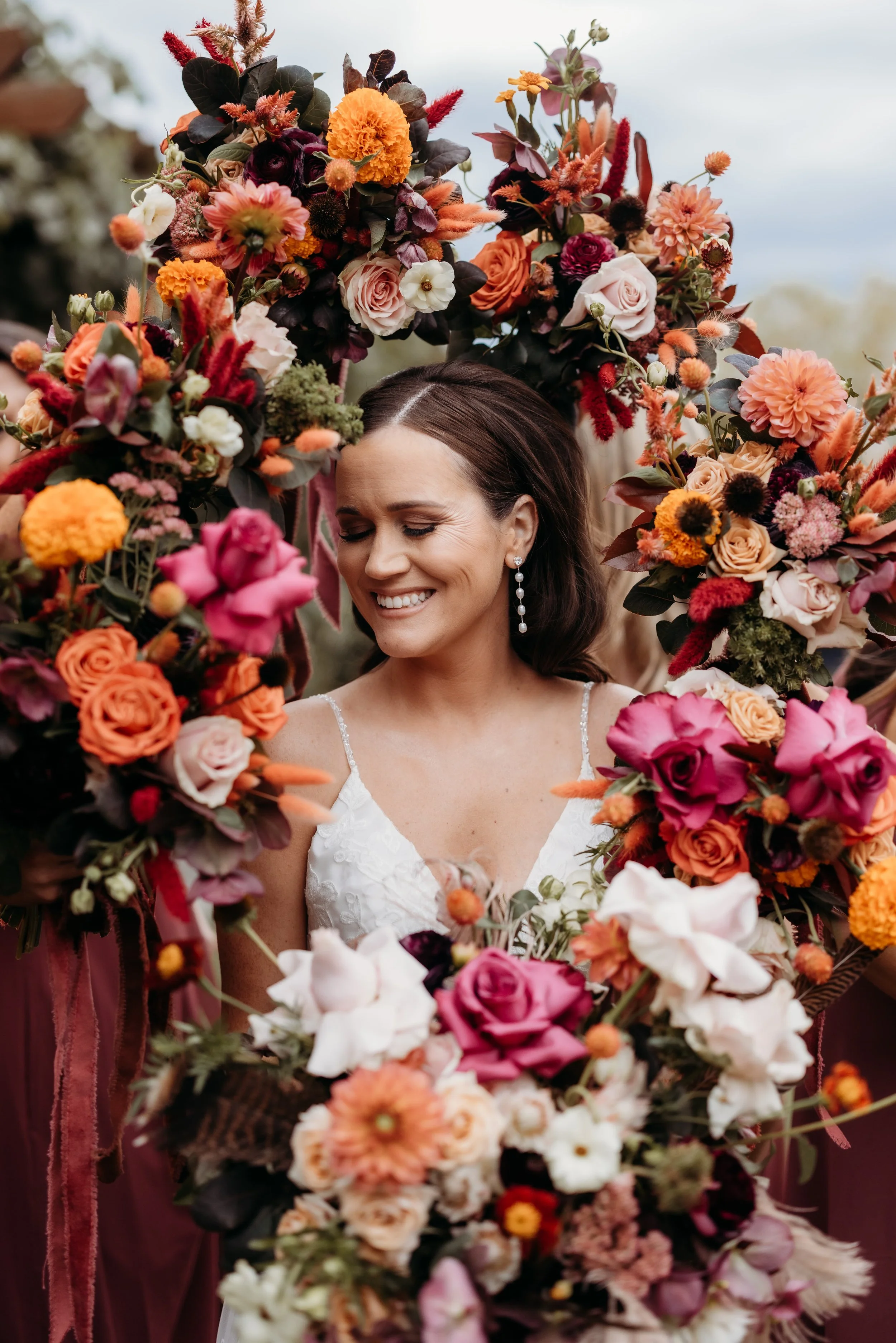 Bouquets of flowers surrounding a smiling bride.