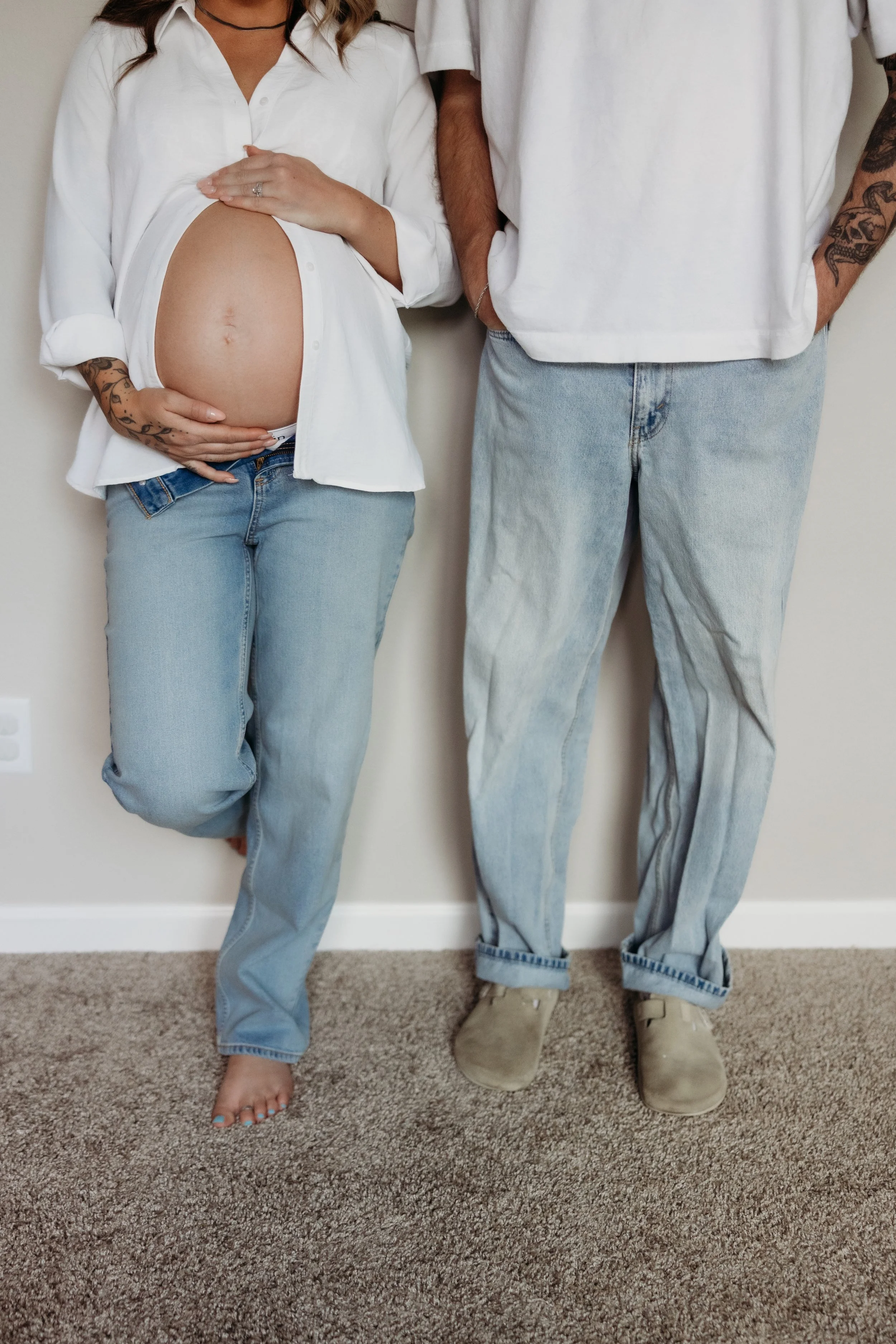 Pregnant woman and her partner leaning against a wall.