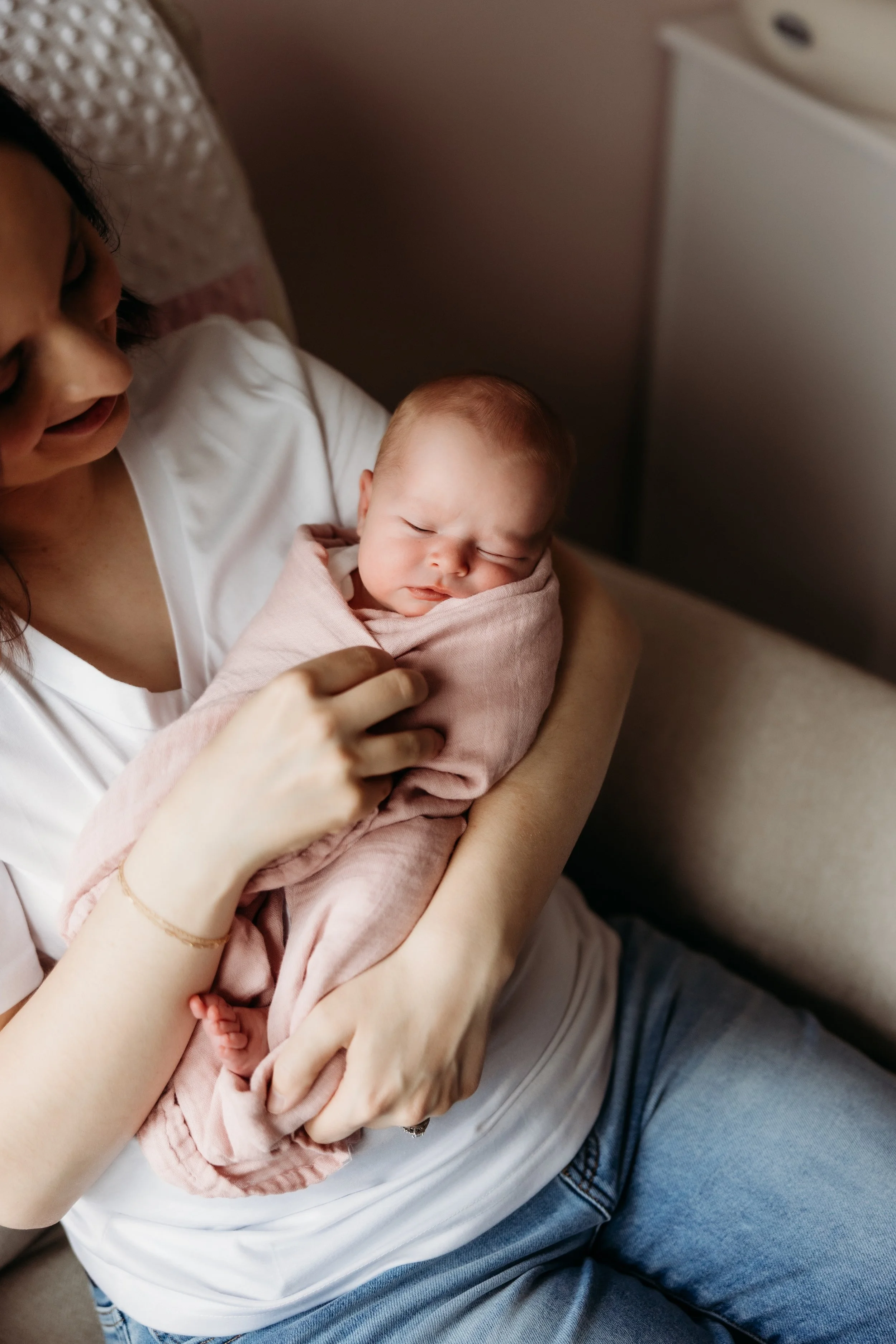 Woman in a rocking chair holding a sleeping newborn.