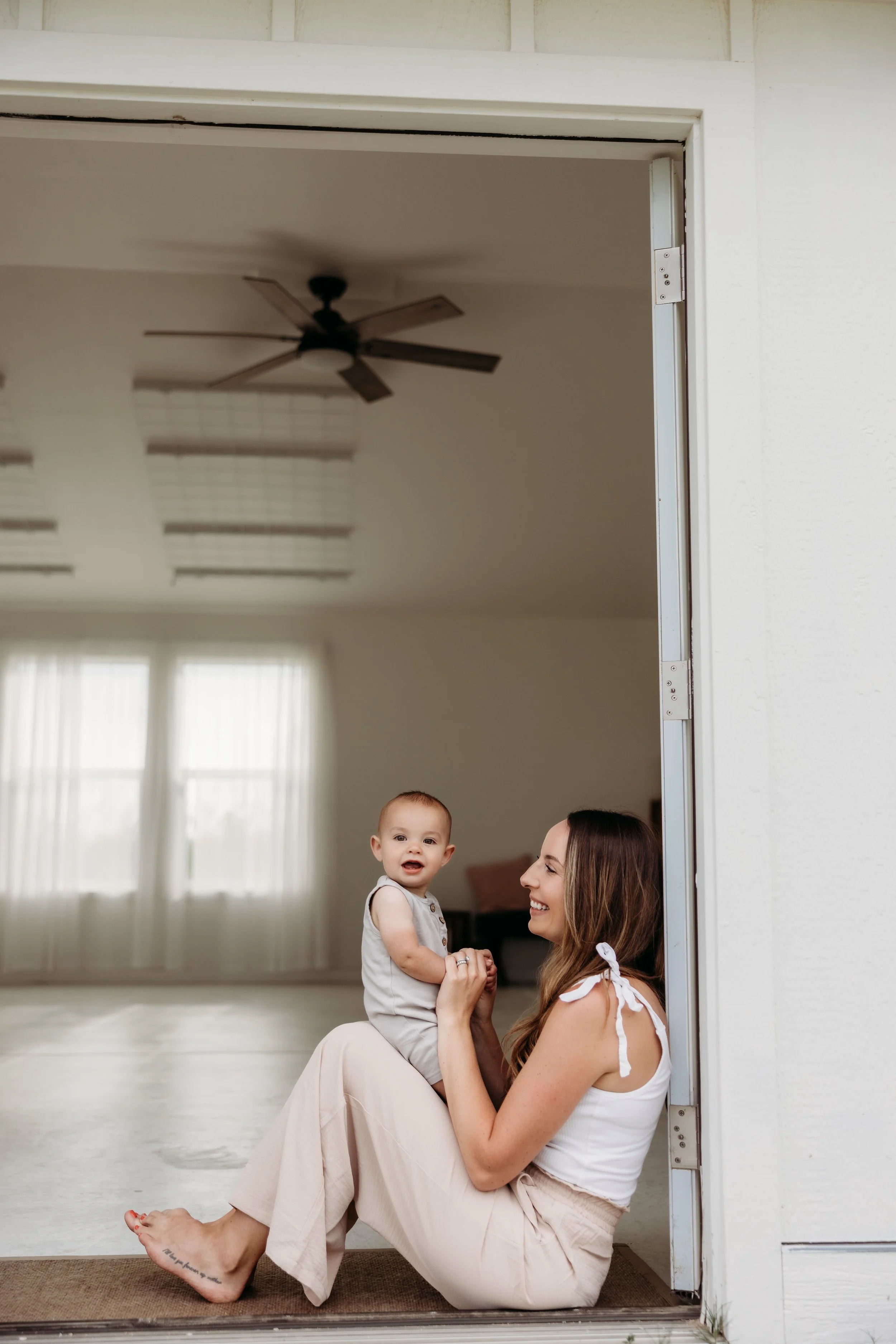 Woman sitting in a doorway holding her smiling baby.