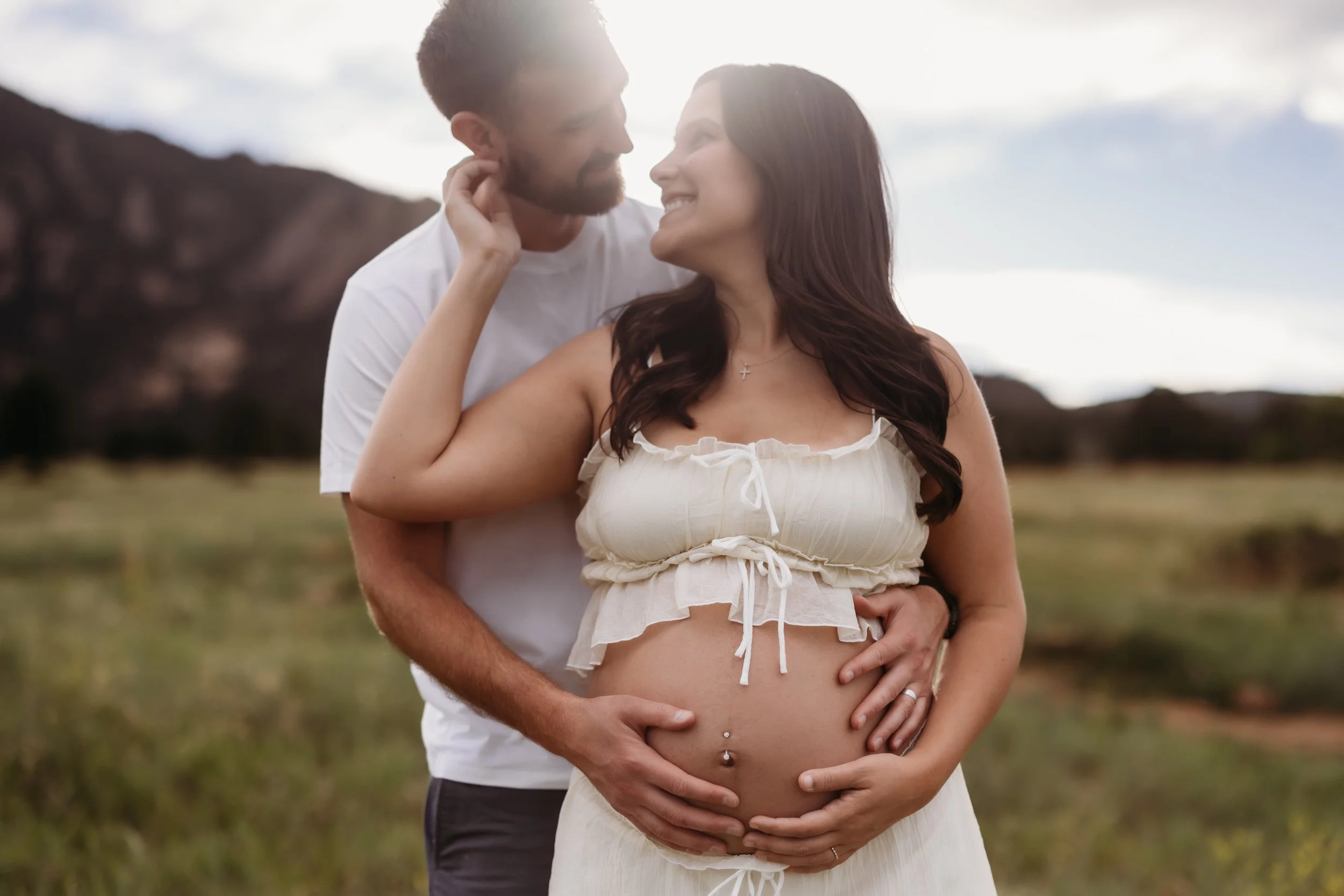 Expectant father embracing his partner's pregnant belly in Boulder, Colorado.