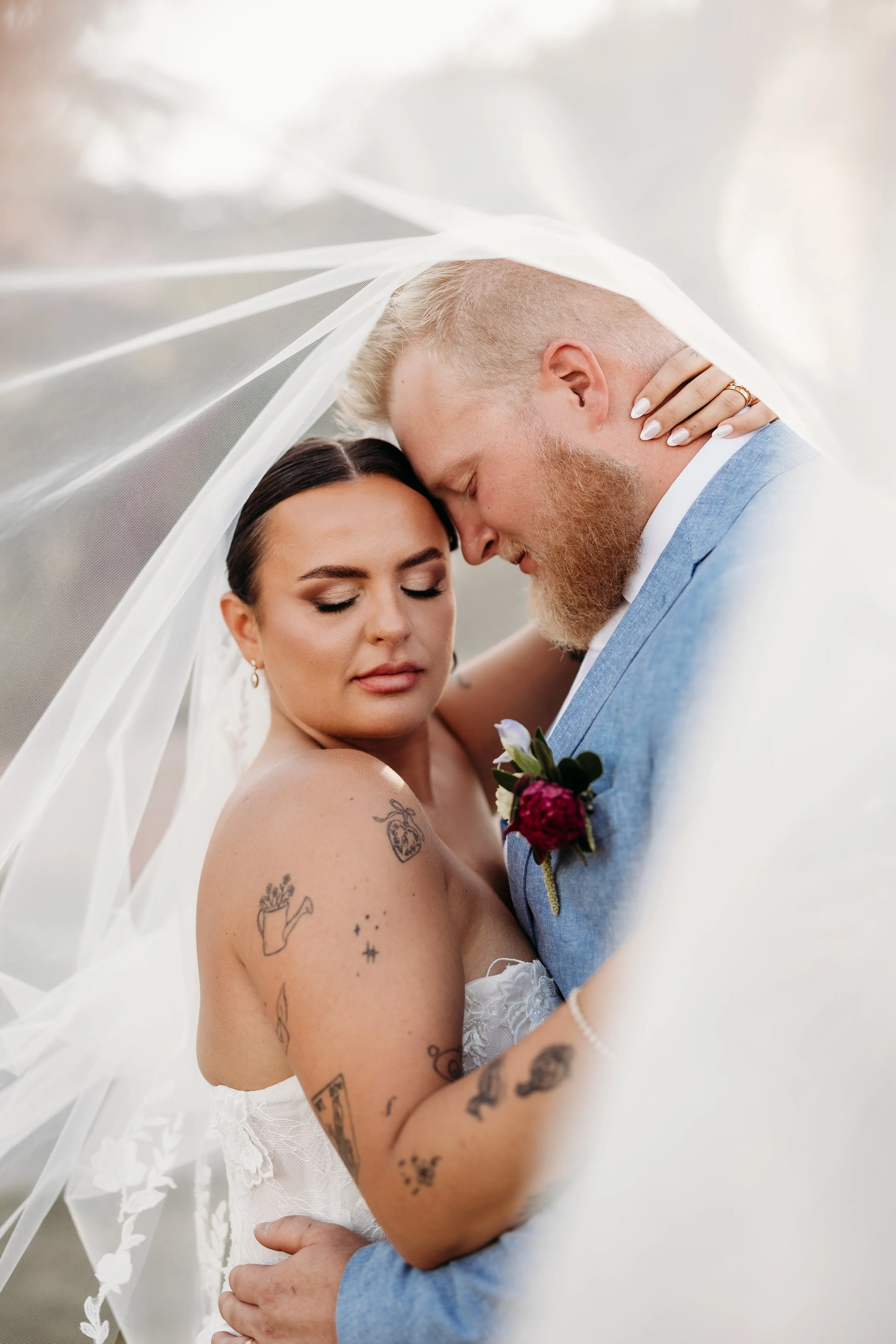 Bride and groom embracing under a veil.