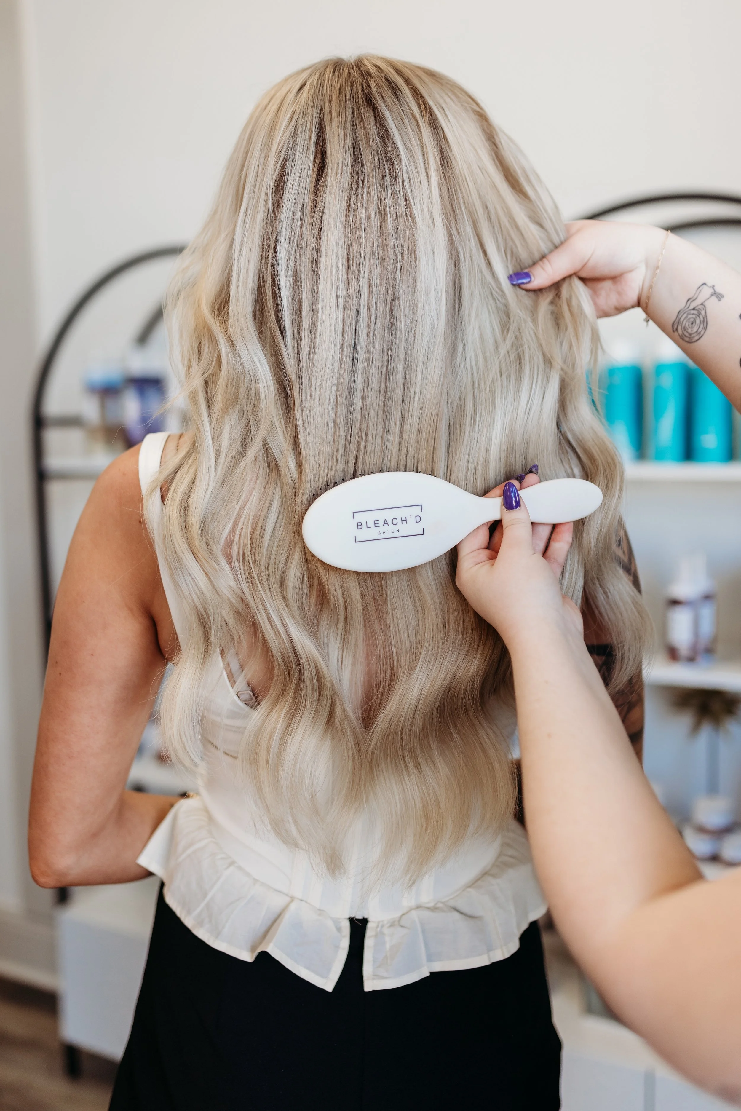 Blonde woman getting her hair brushed at Bleach'd Salon.
