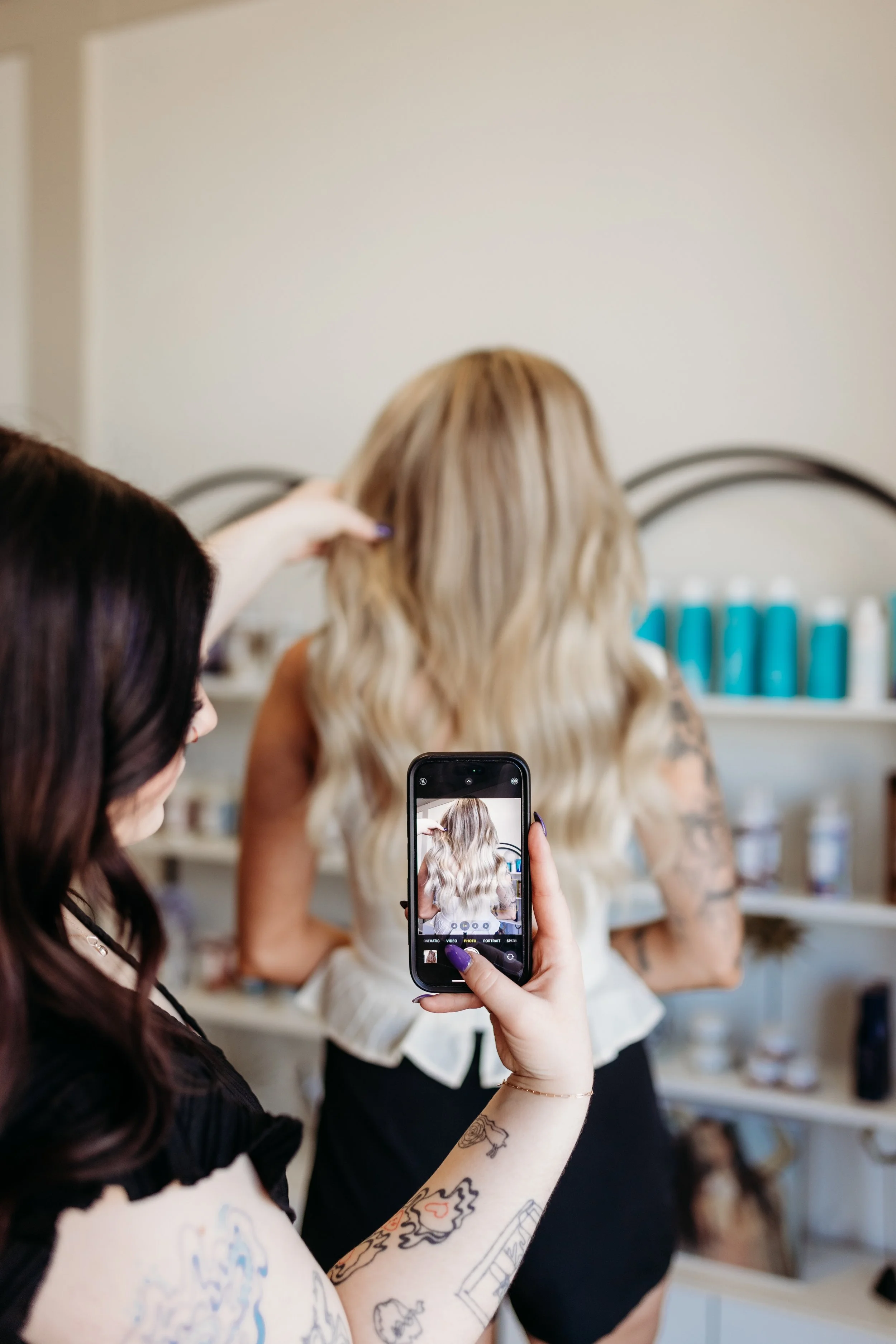 A woman taking a photo of another woman with blonde hair.