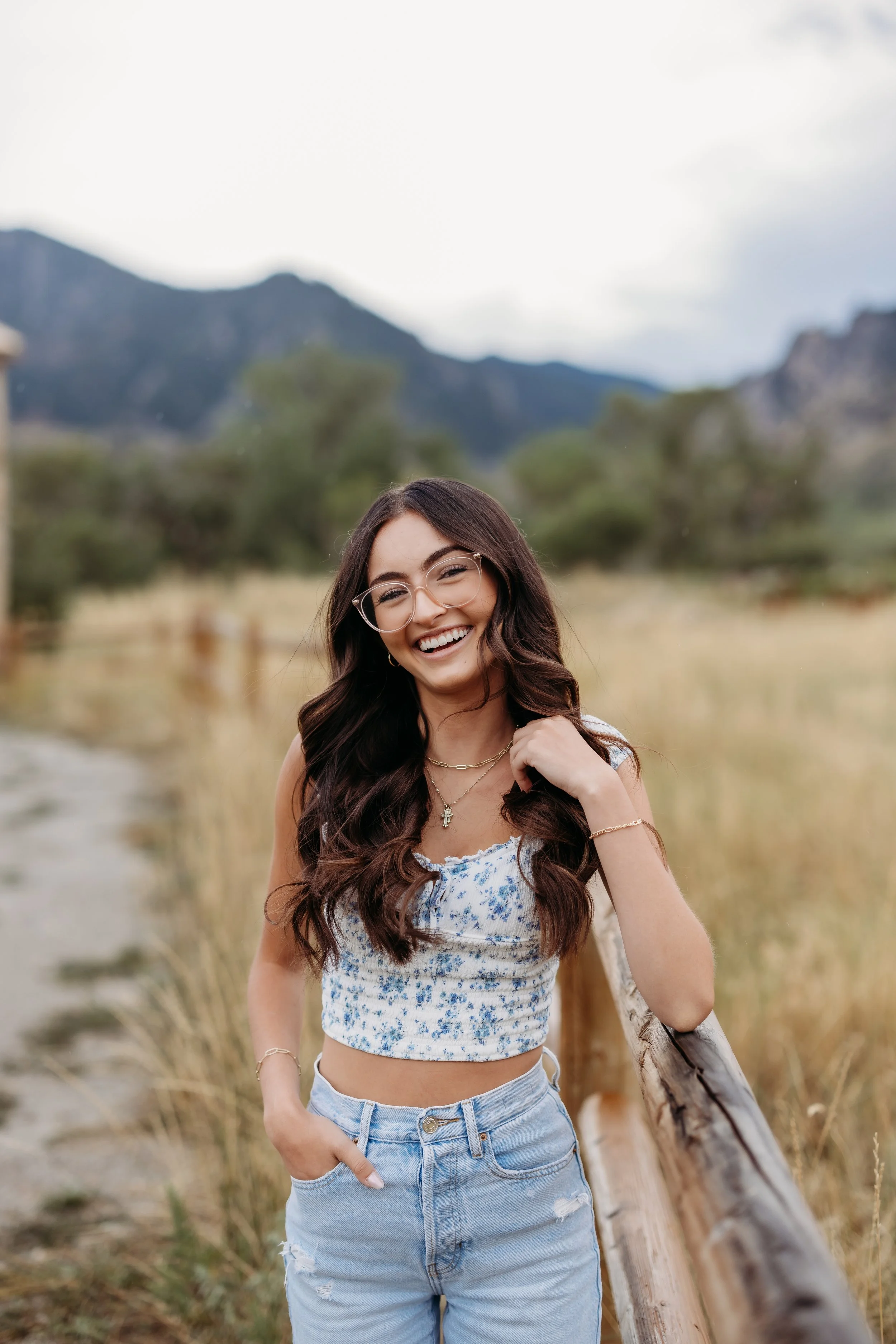 A smiling teenage girl leaning on a fence at Chautauqua Park in Boulder, Colorado.