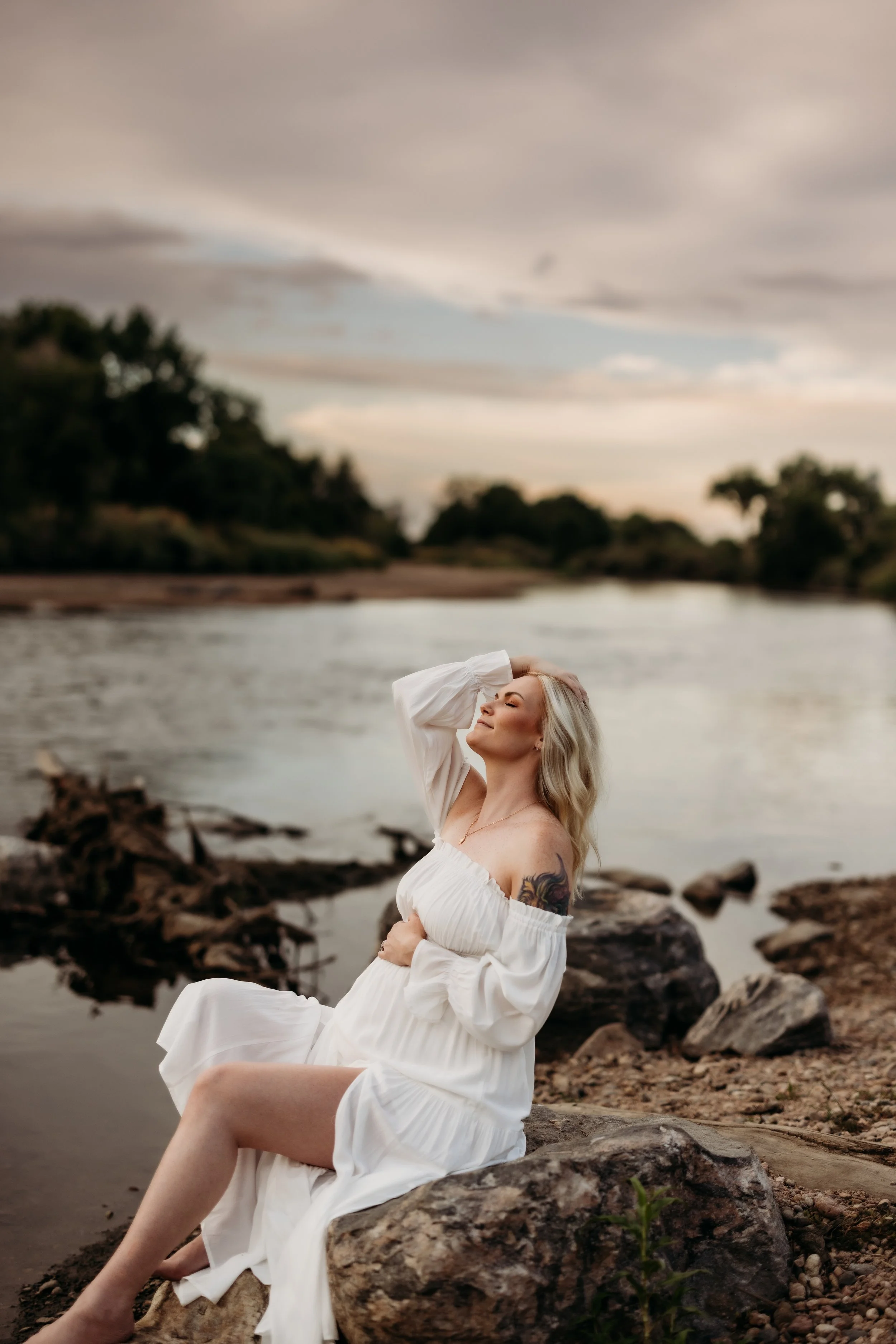 Pregnant woman posing on a rock at a lake in Littleton, Colorado.