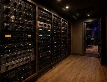 Row of vintage radios behind glass display cabinets in a dimly lit room.