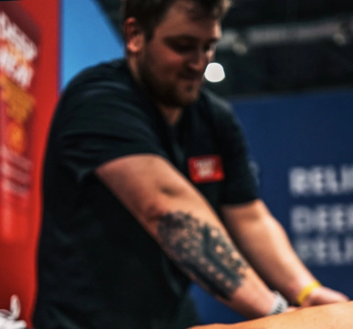 Sports therapist delivering hands on recovery treatment to an athlete at a HYROX fitness event to support muscle recovery, movement and performance.