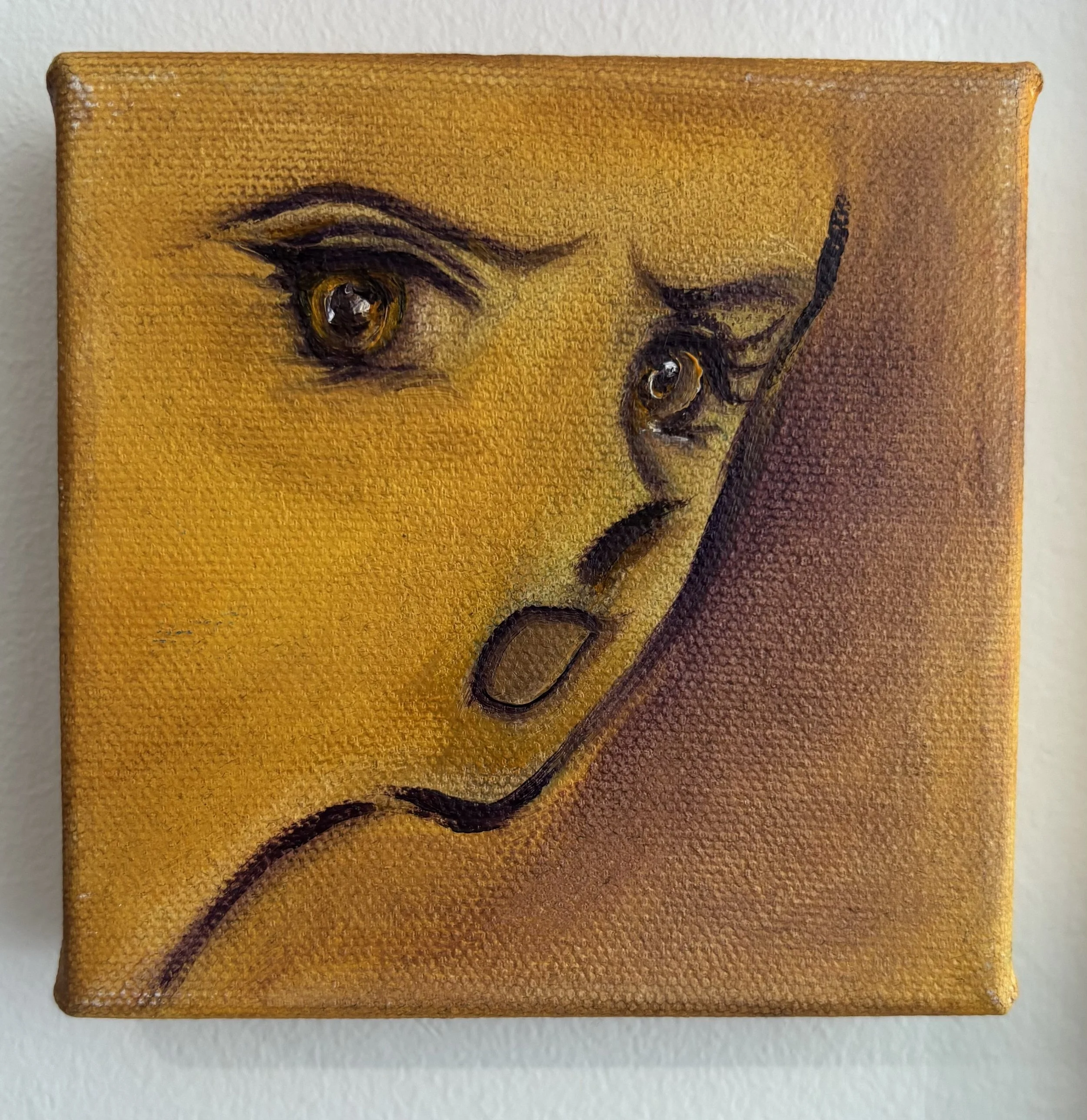 Close-up of a small canvas painting showing a female face with large expressive eyes, slightly parted lips, and long flowing hair against a yellow background.